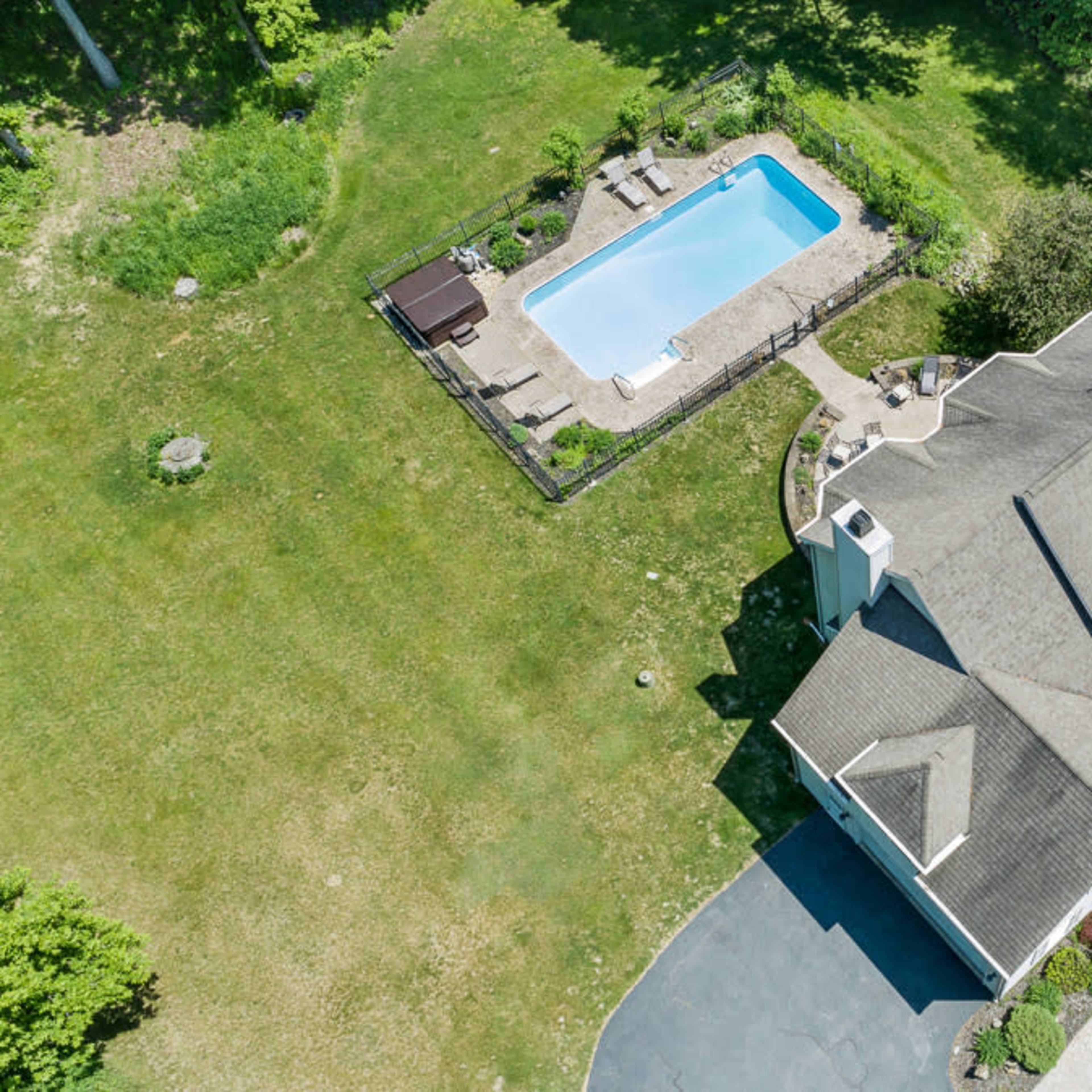 An aerial view of a house with a pool surrounded by a landscaped yard.
