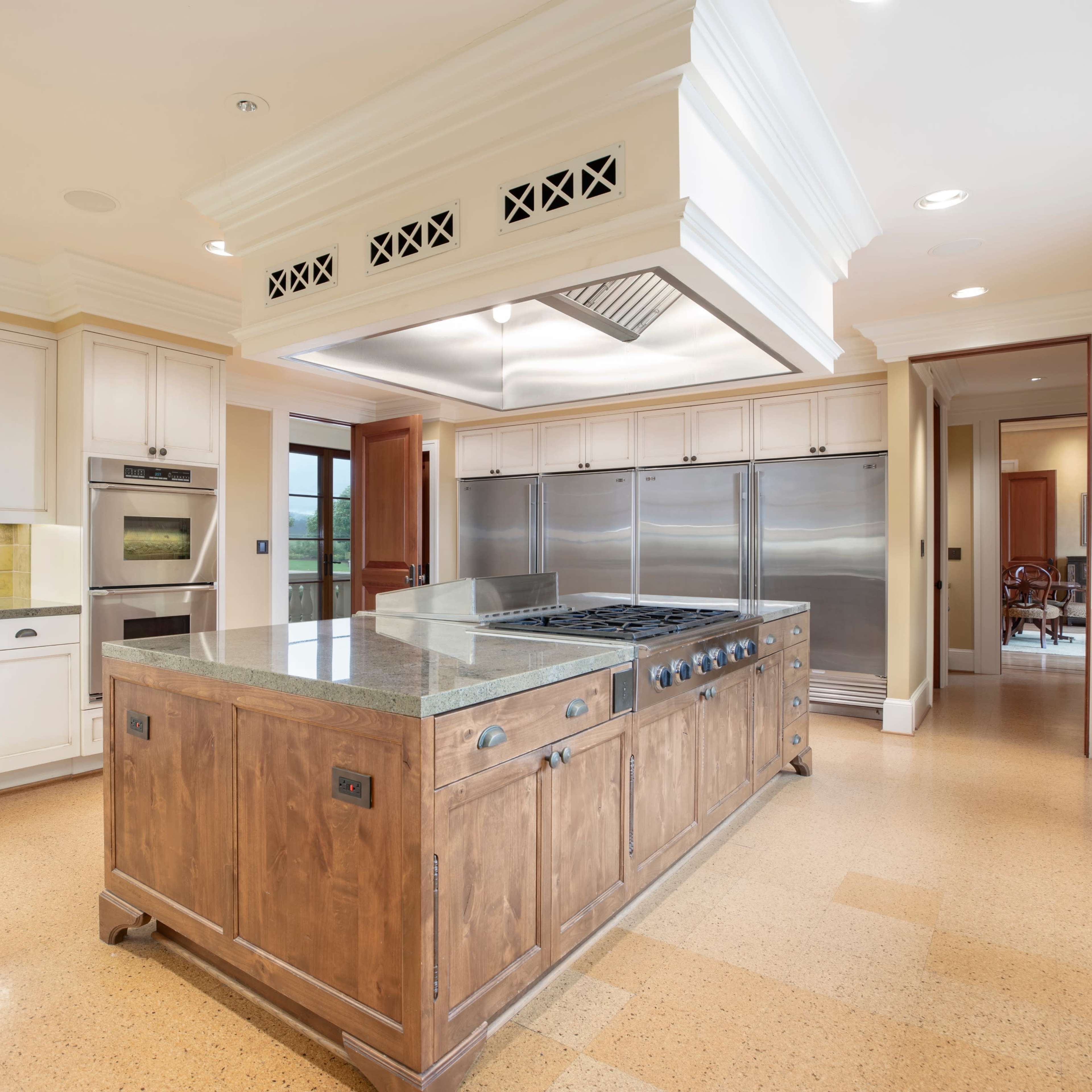 A spacious kitchen with light cabinetry, stainless steel appliances, and a central island featuring a gas cooktop.