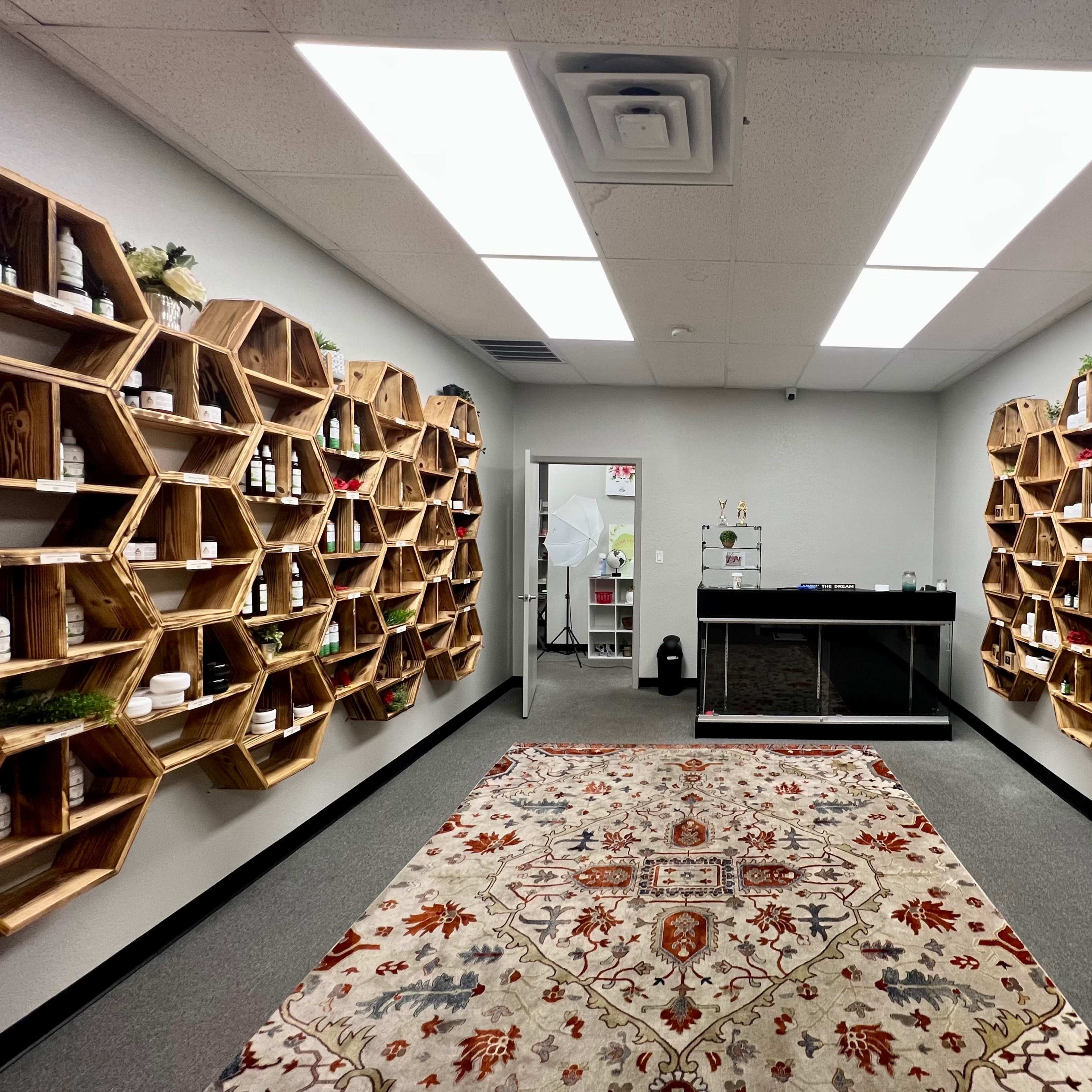 A modern retail space with hexagon-shaped wooden shelves lined with products and a central checkout counter, featuring a patterned rug on the floor.