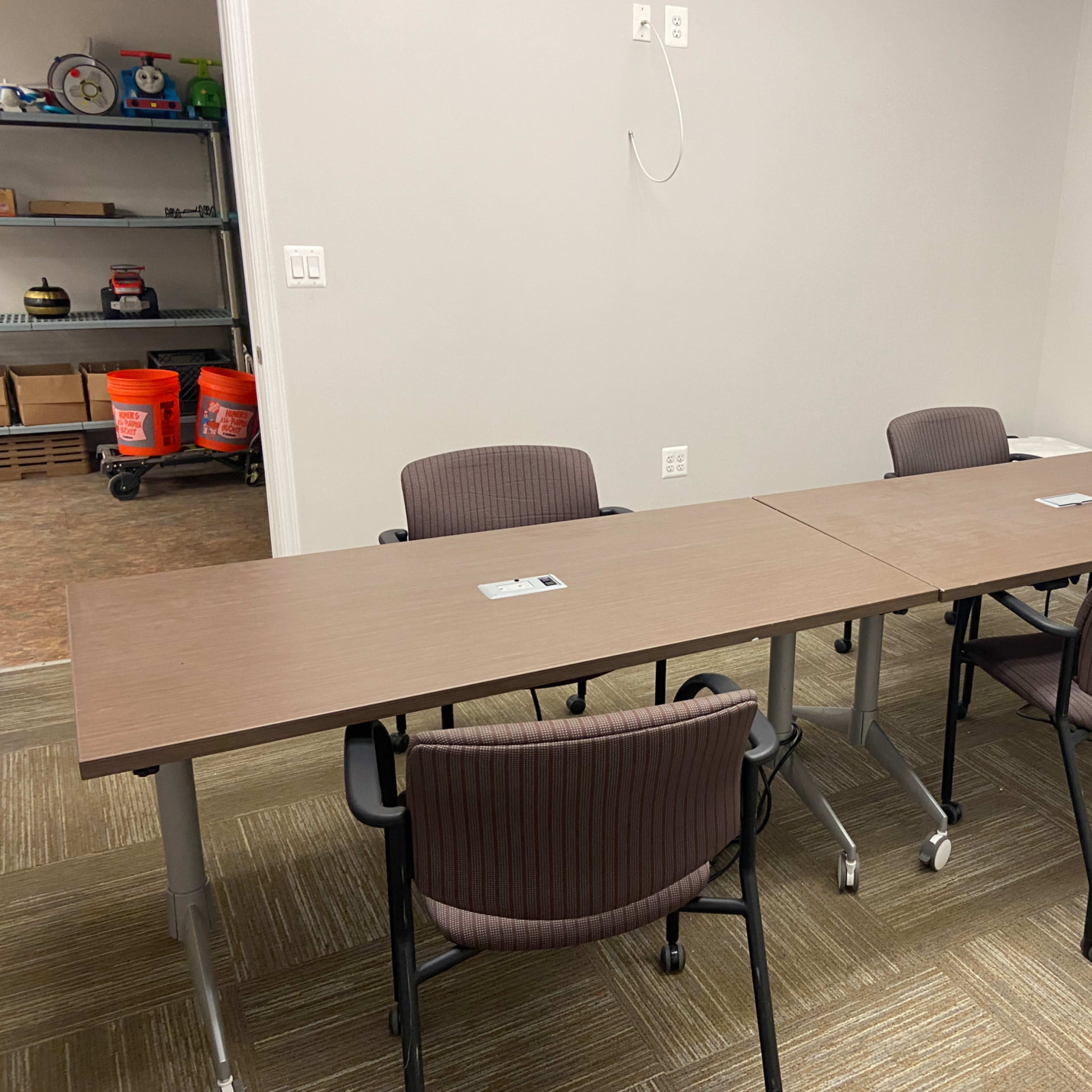 A meeting room features a long table set for four chairs, with office supplies placed at each seat.