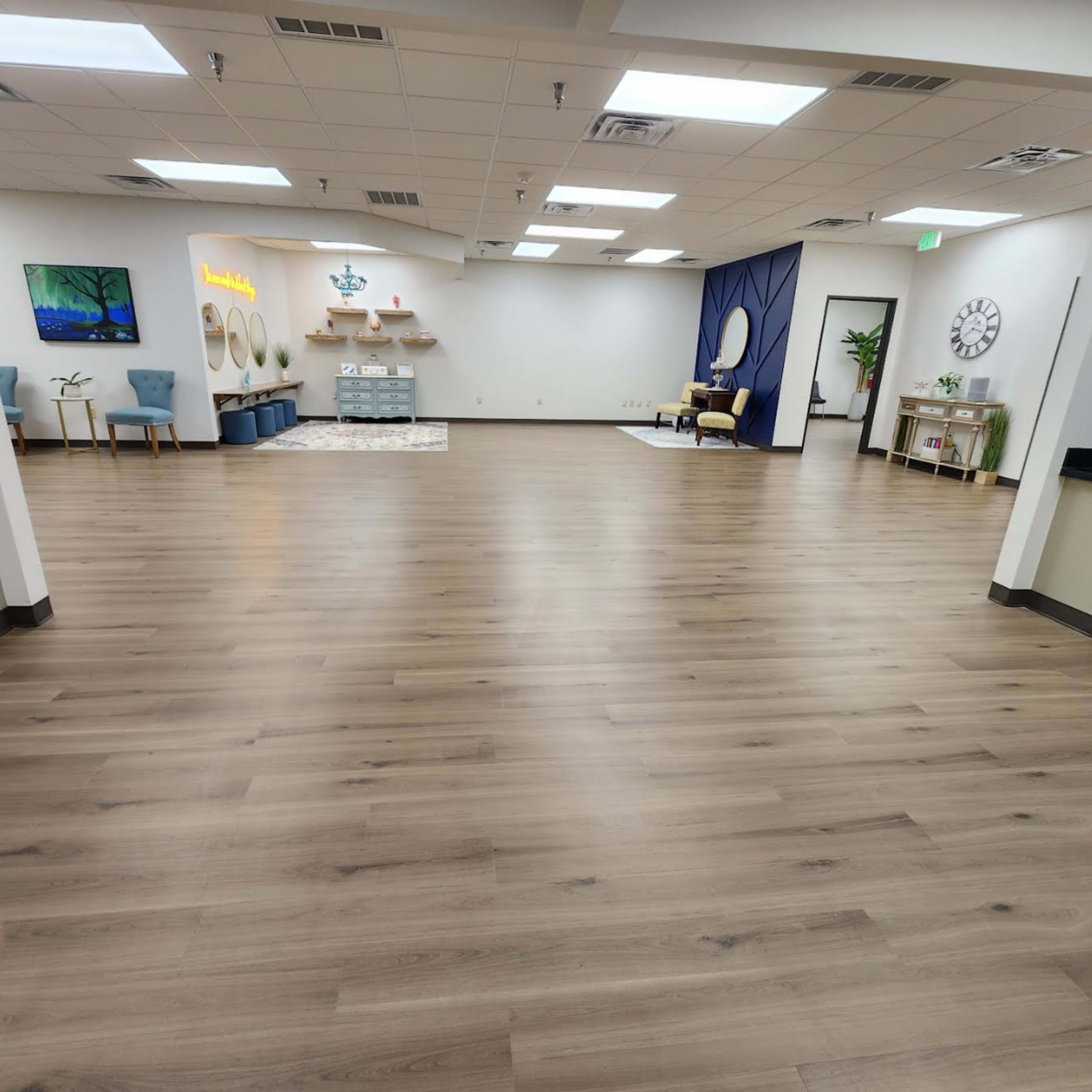 A spacious, empty room with wooden flooring, a seating area, and decorative elements along the walls.