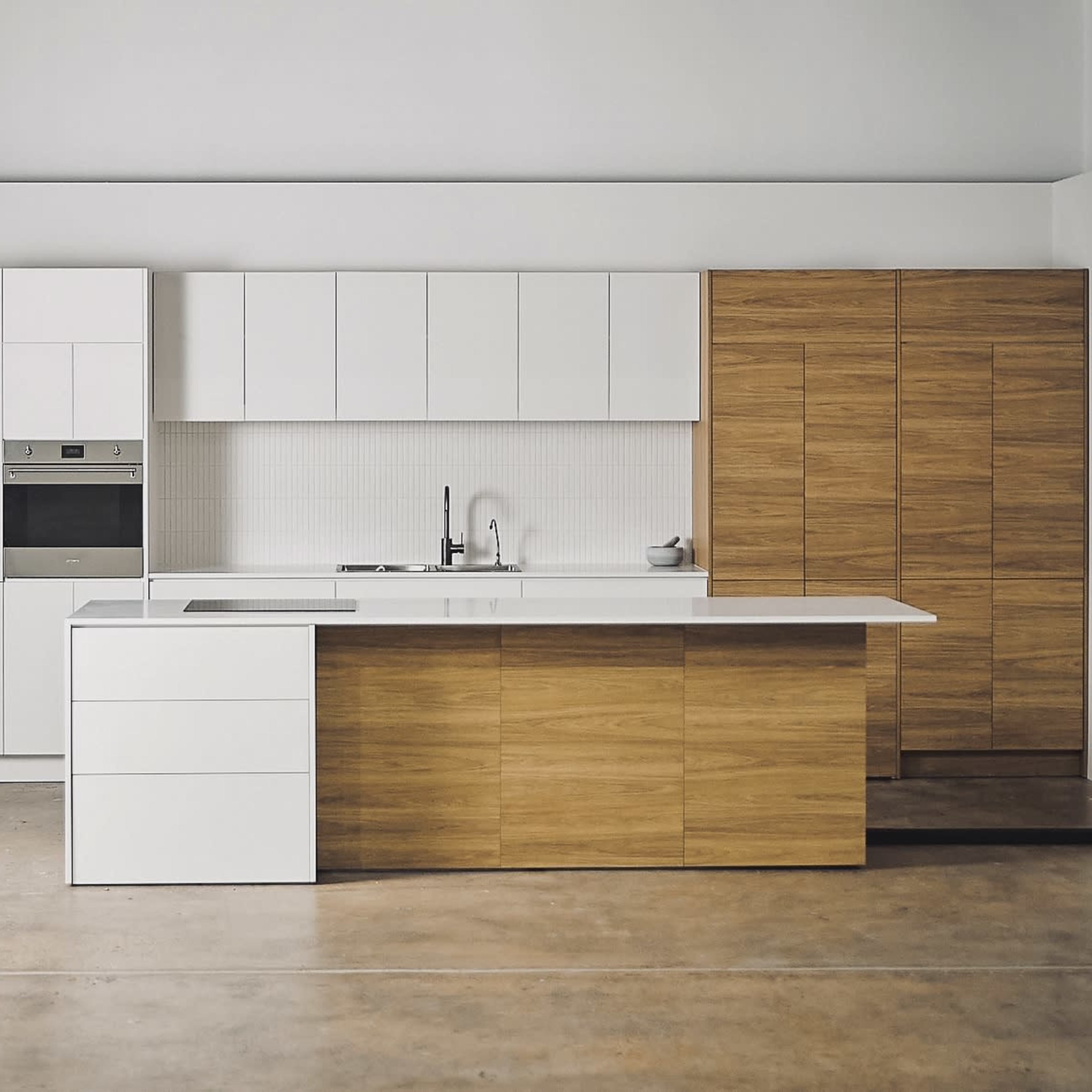 A modern kitchen featuring white cabinets and a wooden island with smooth surfaces and minimalistic design.