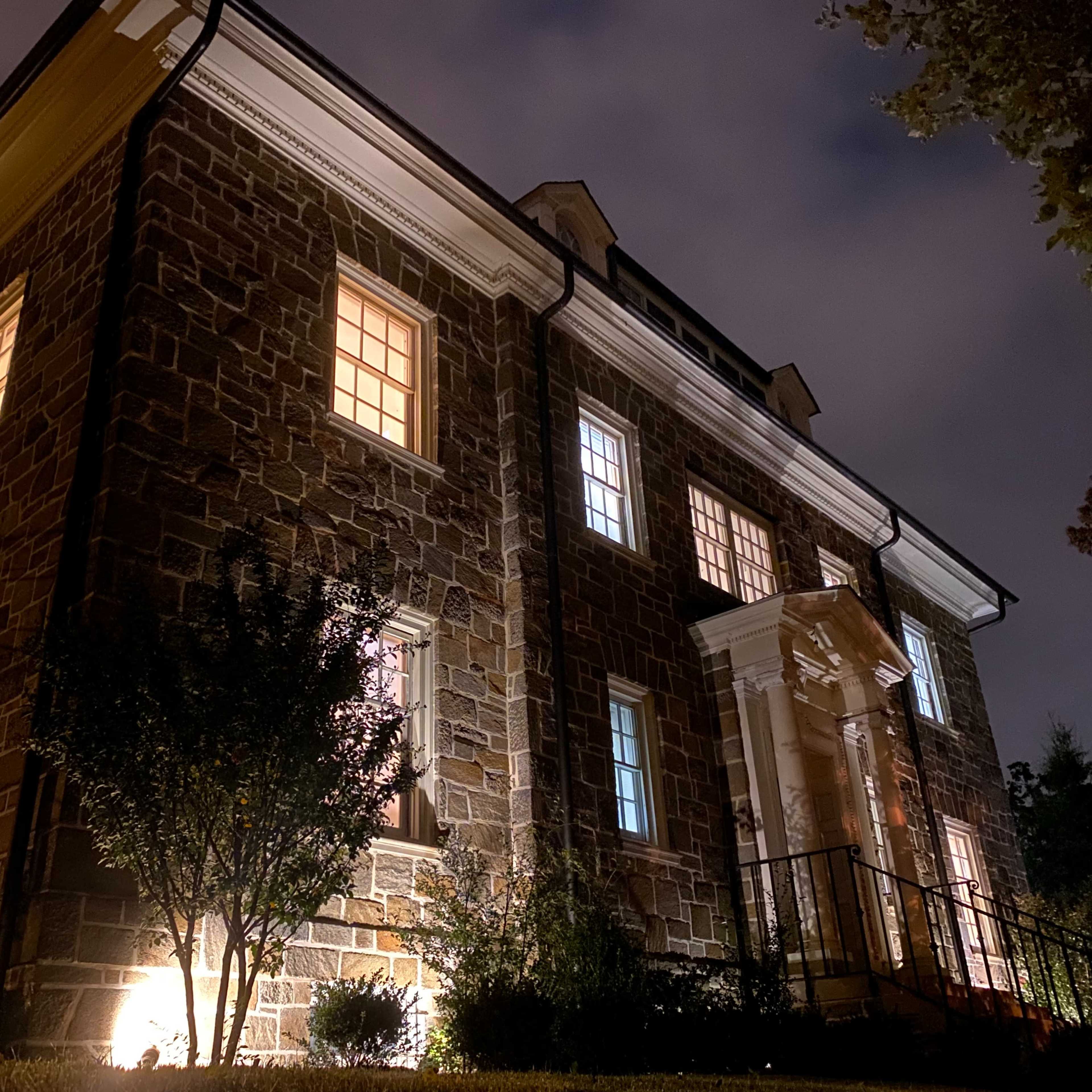 A stone building with illuminated windows is set against a night sky.