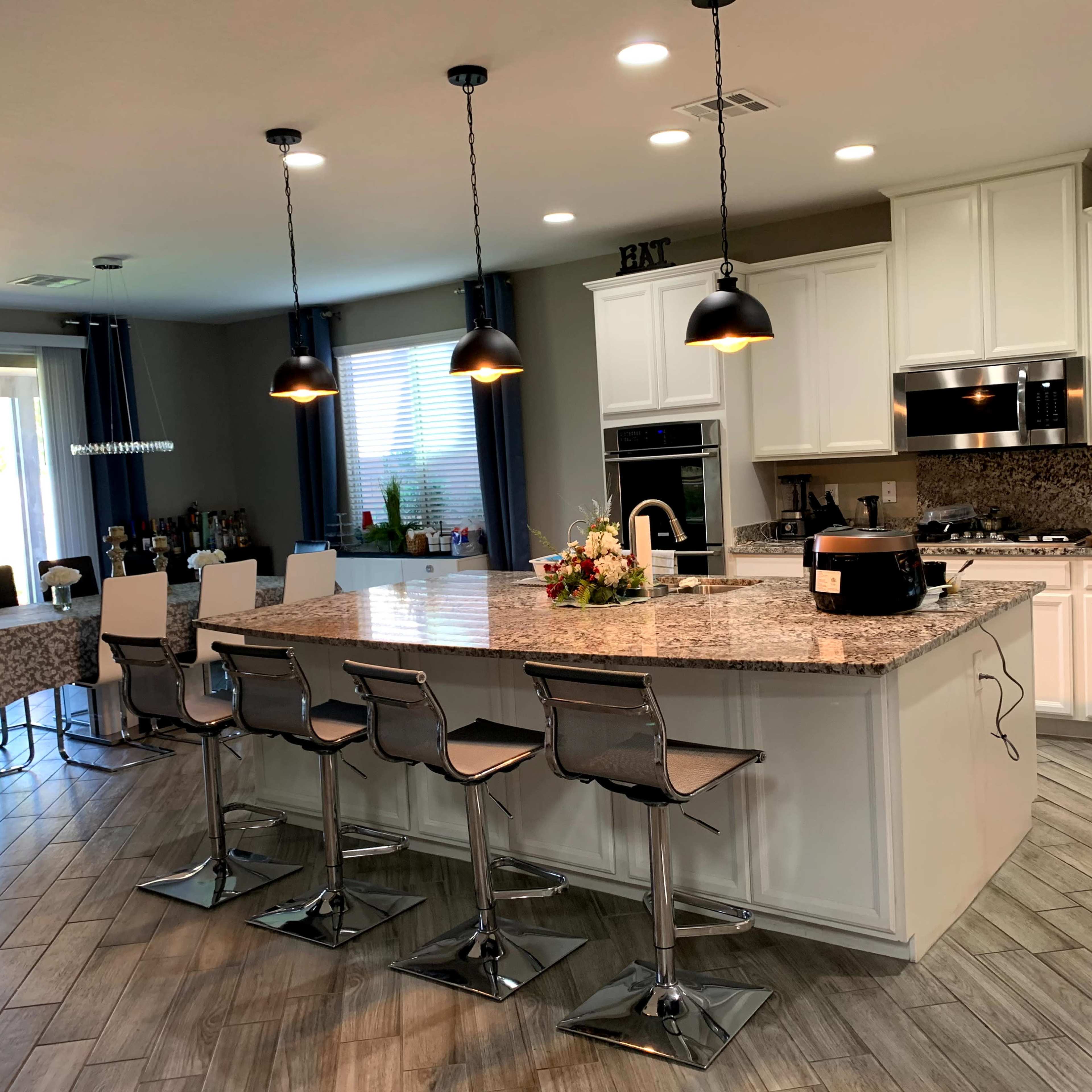 The kitchen features a large island with seating, modern appliances, and natural light coming from a sliding glass door.