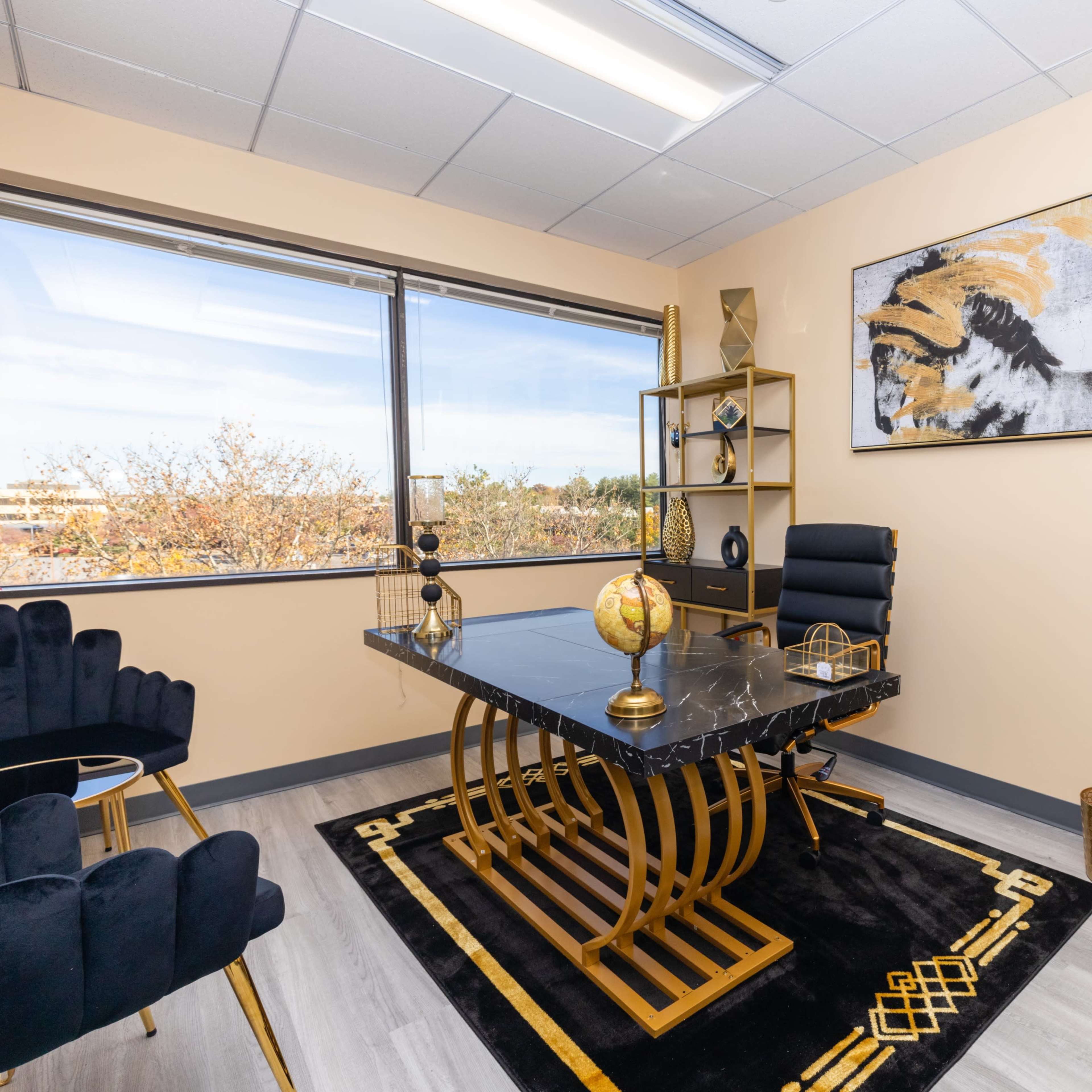 A modern office space featuring a black marble desk, gold accents, and a large window that allows natural light to enter.