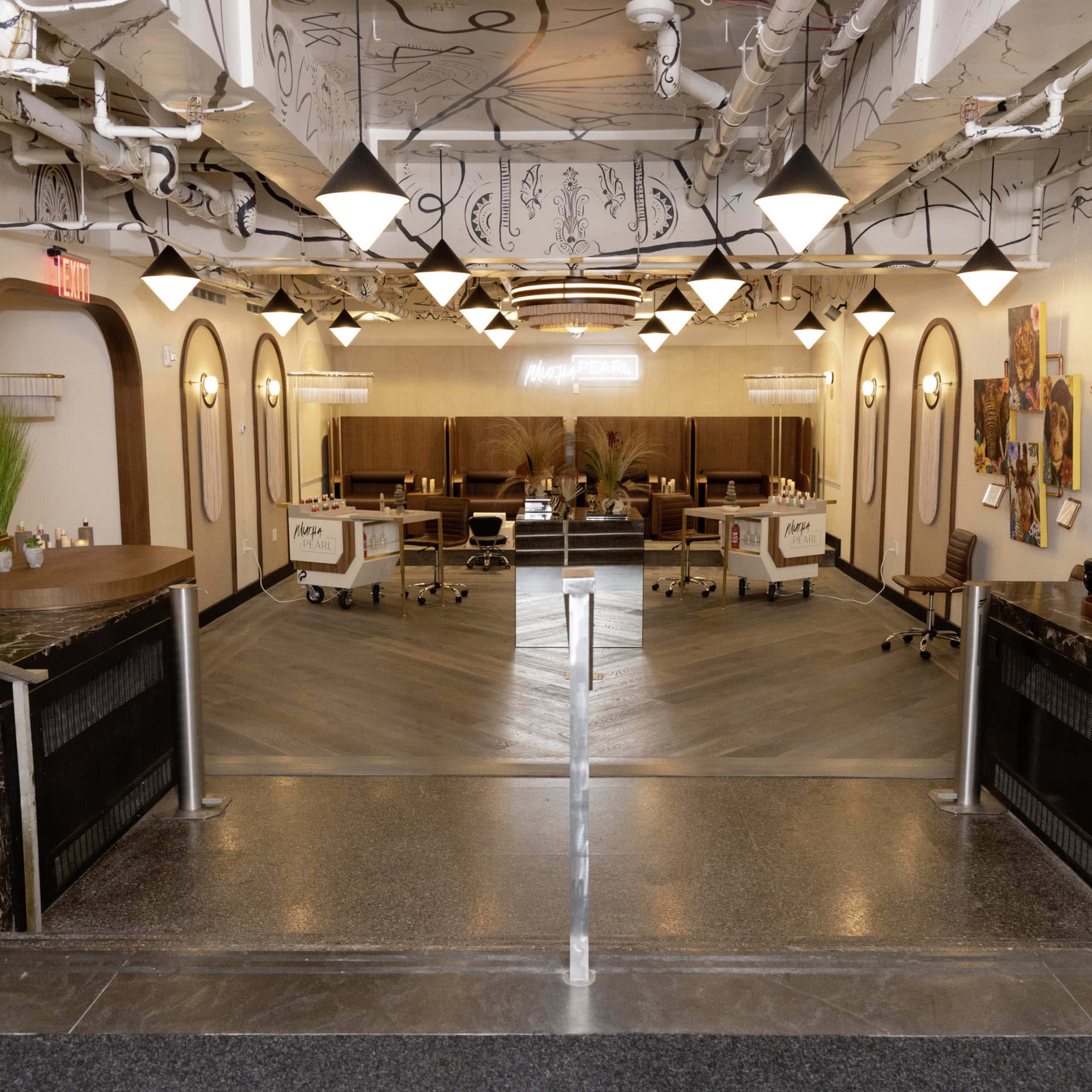 A modern salon interior featuring workstations with chairs, elegant lighting fixtures, and a decorative layout.