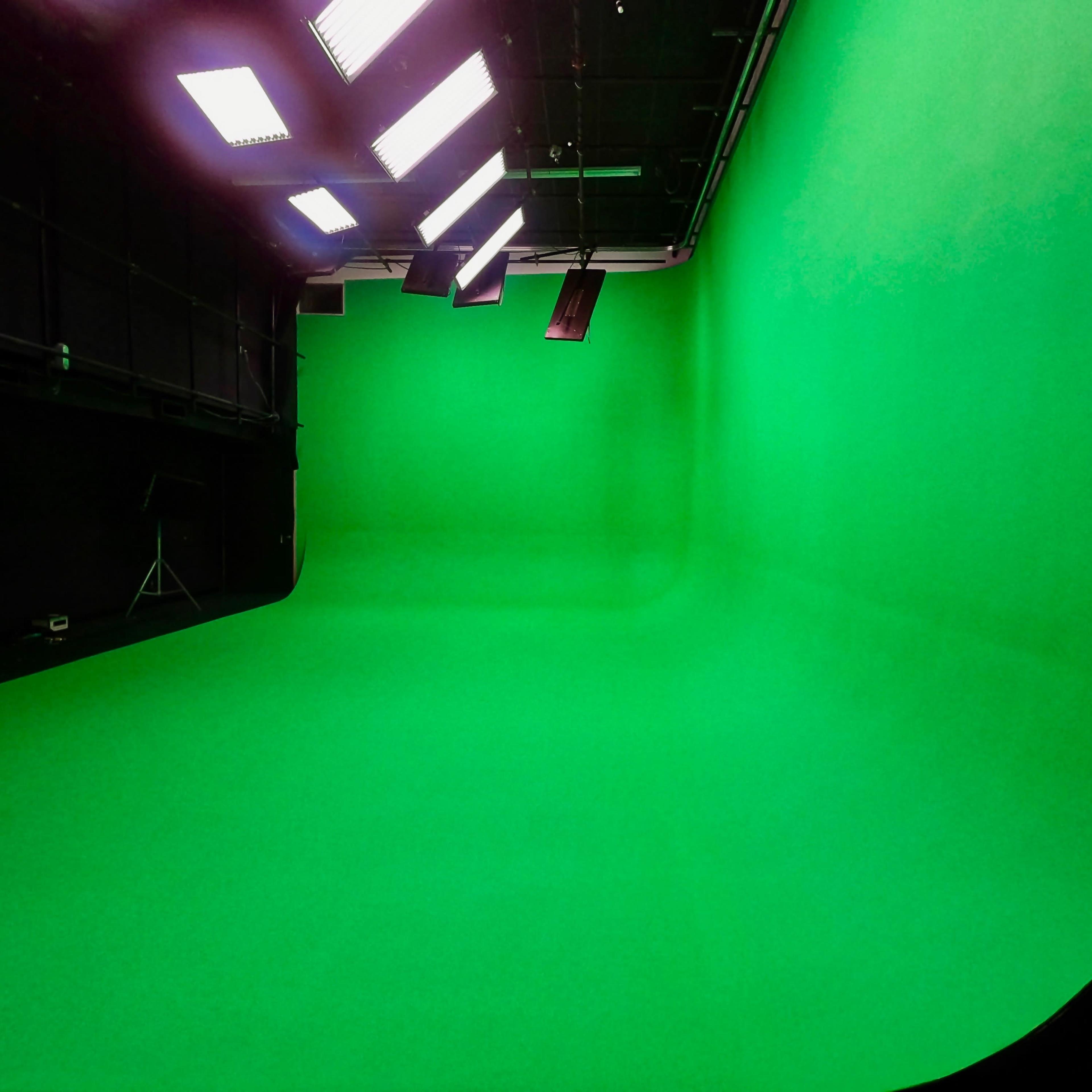 A green screen studio with a seamless green backdrop and overhead lights.