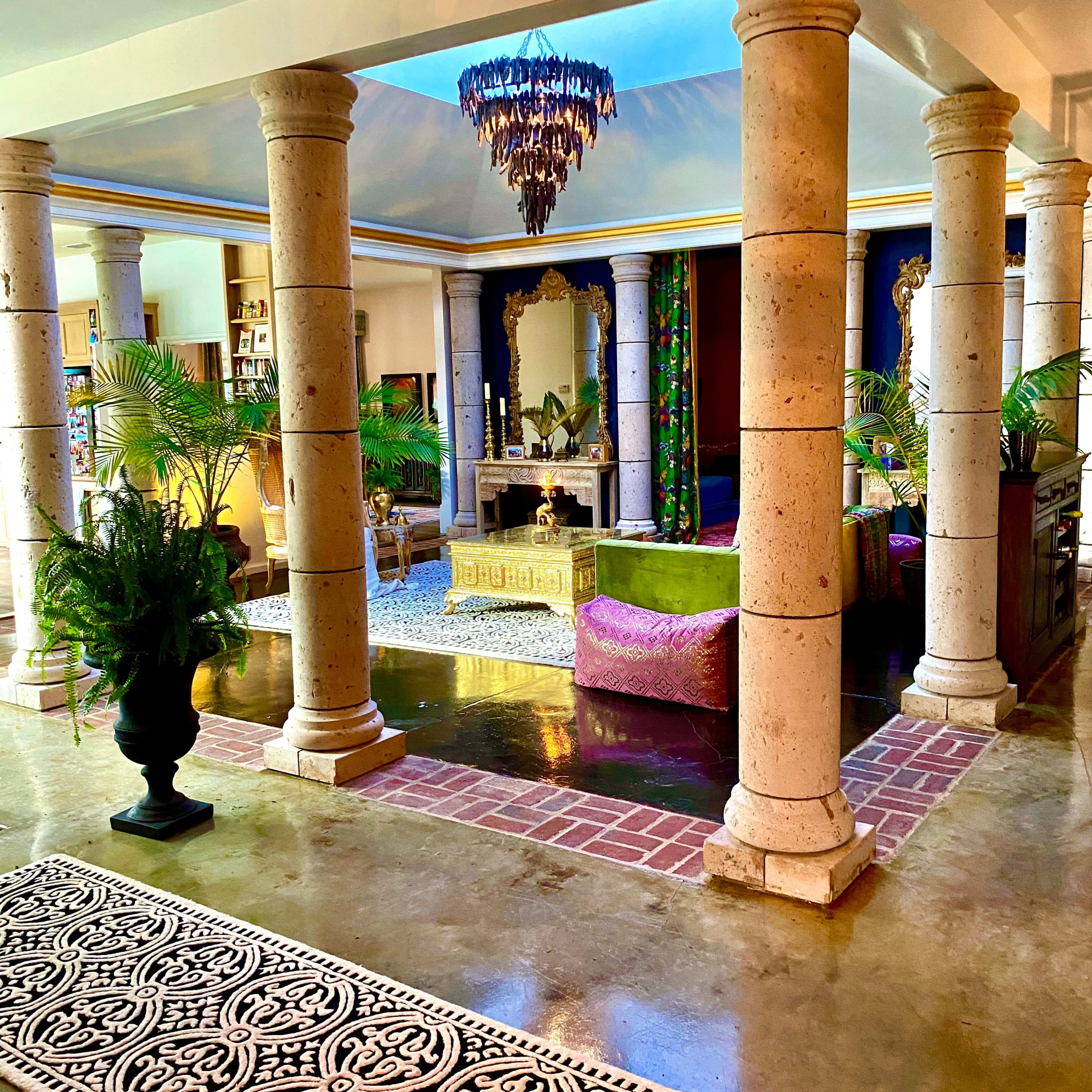 The interior features columns supporting a ceiling, with a vibrant seating area and decorative elements creating an open, inviting space.