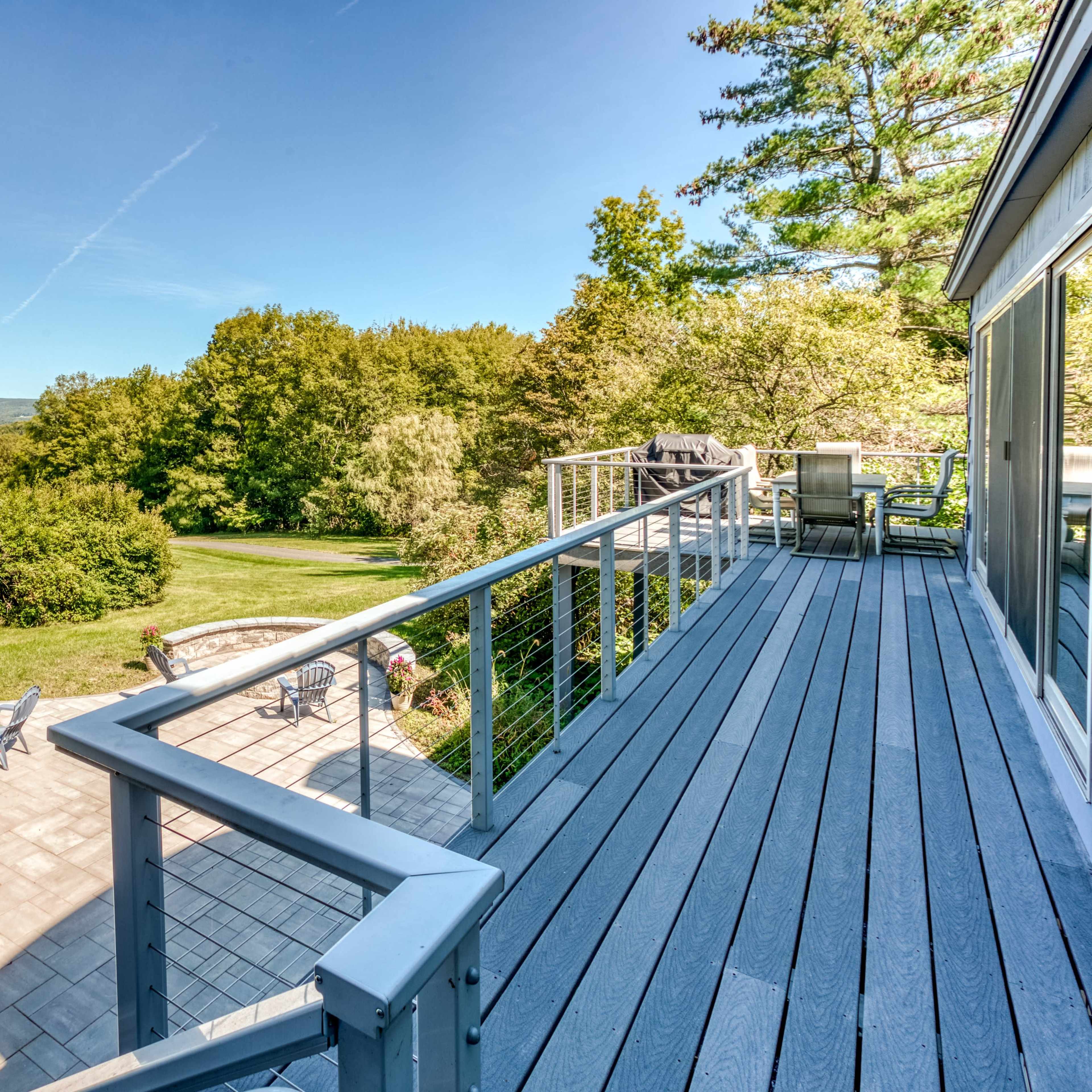 A deck overlooking a landscaped yard with trees and mountains in the distance.