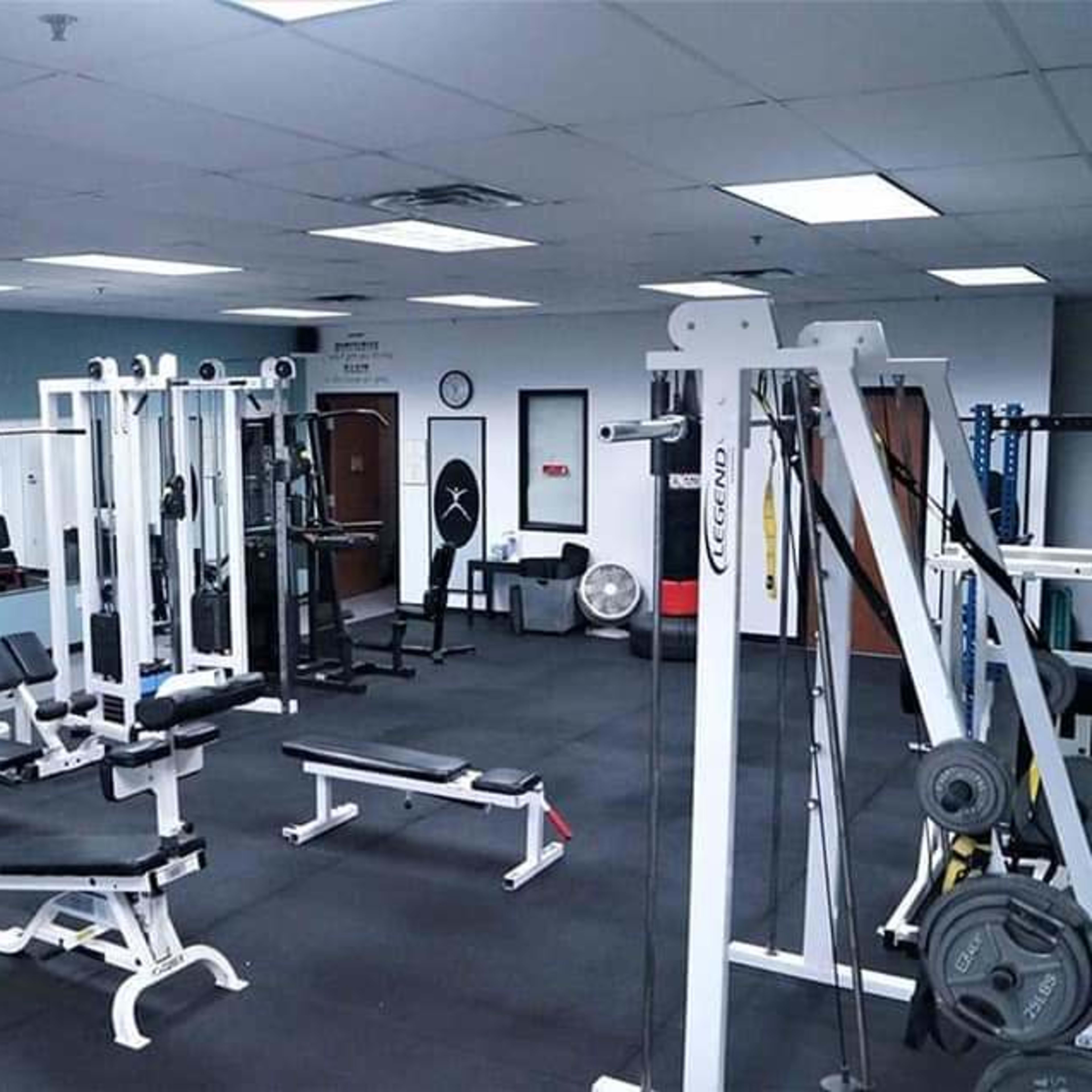 A gym interior with various workout machines, benches, and mirrors arranged in a spacious layout.