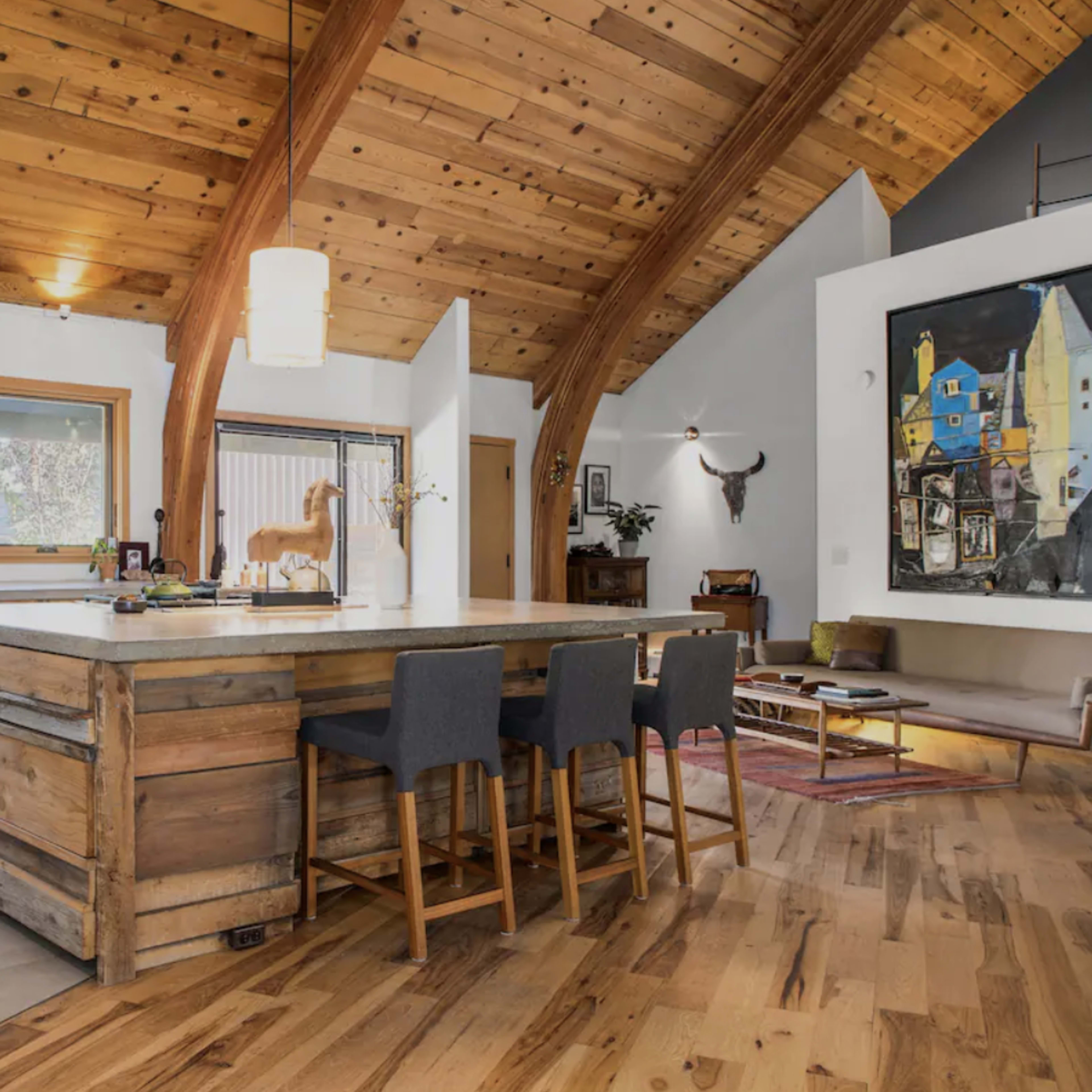 A modern kitchen with an island, wooden beams, and a combination of rustic and contemporary design elements.