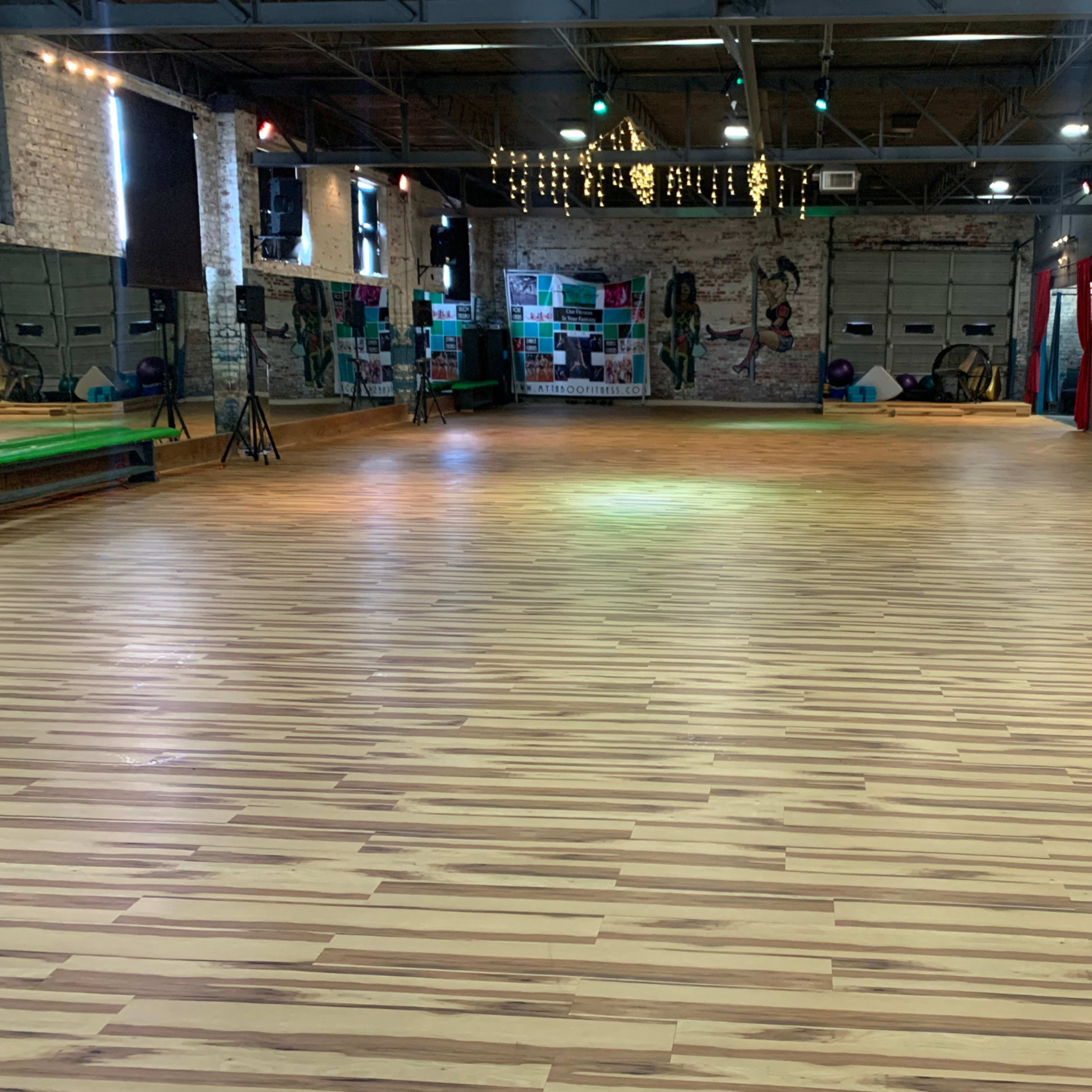 A spacious, wooden-floored gymnasium with mirrored walls and colorful decor.