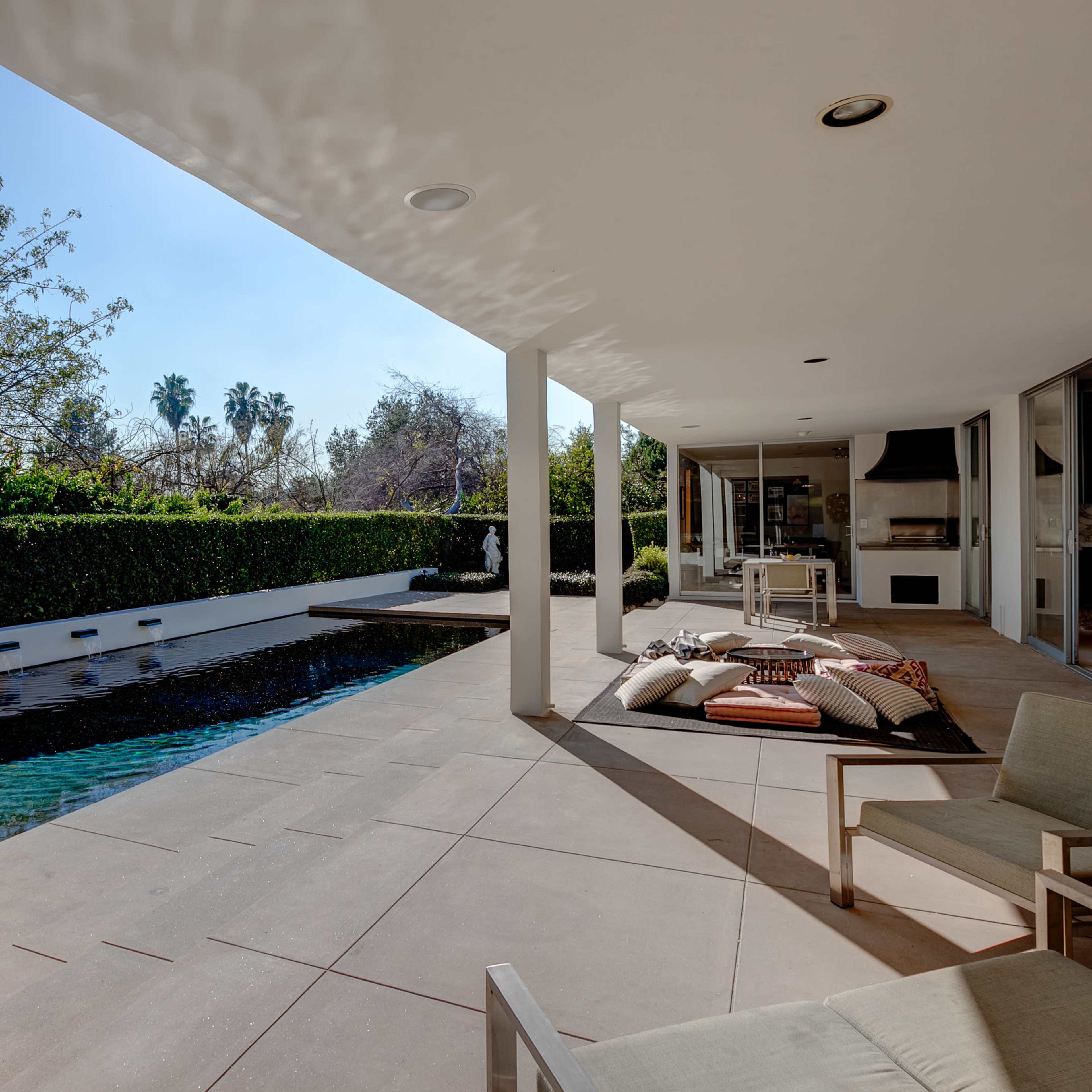 A modern patio area with a swimming pool, surrounded by greenery and featuring contemporary seating.