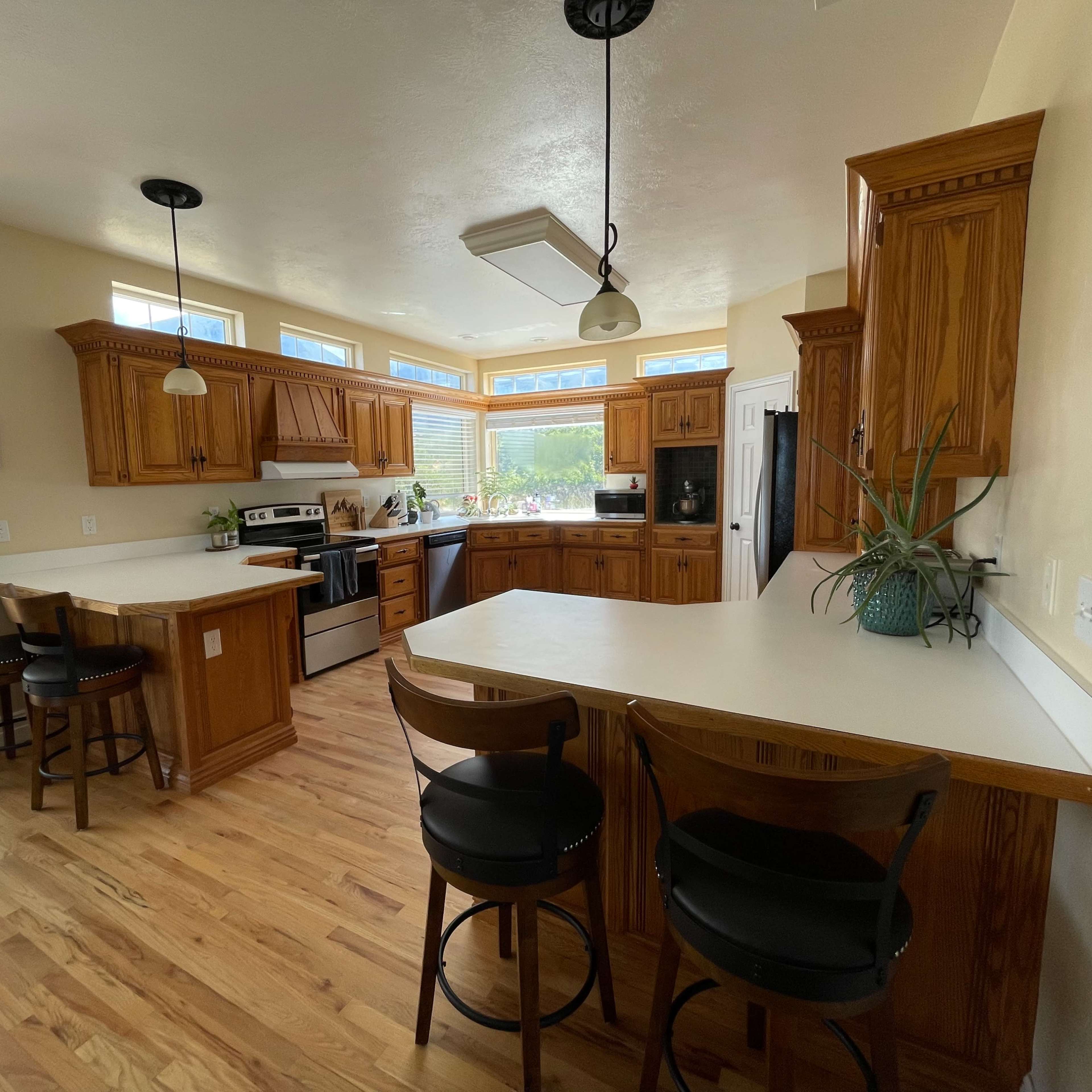 A spacious kitchen with wooden cabinets, a central island with bar seating, and large windows providing natural light.