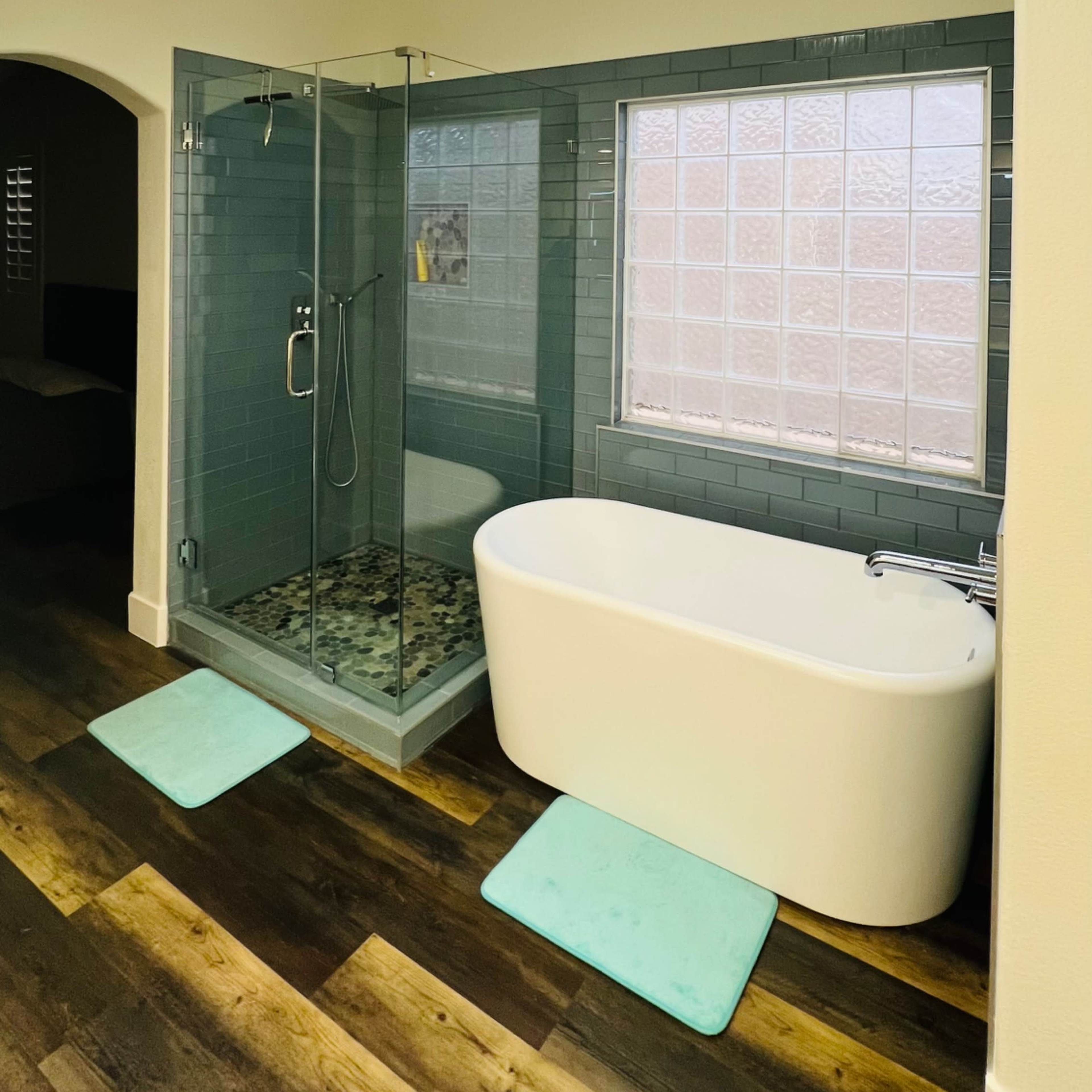 A modern bathroom featuring a glass shower enclosure, a freestanding bathtub, and a circular chandelier hanging above.