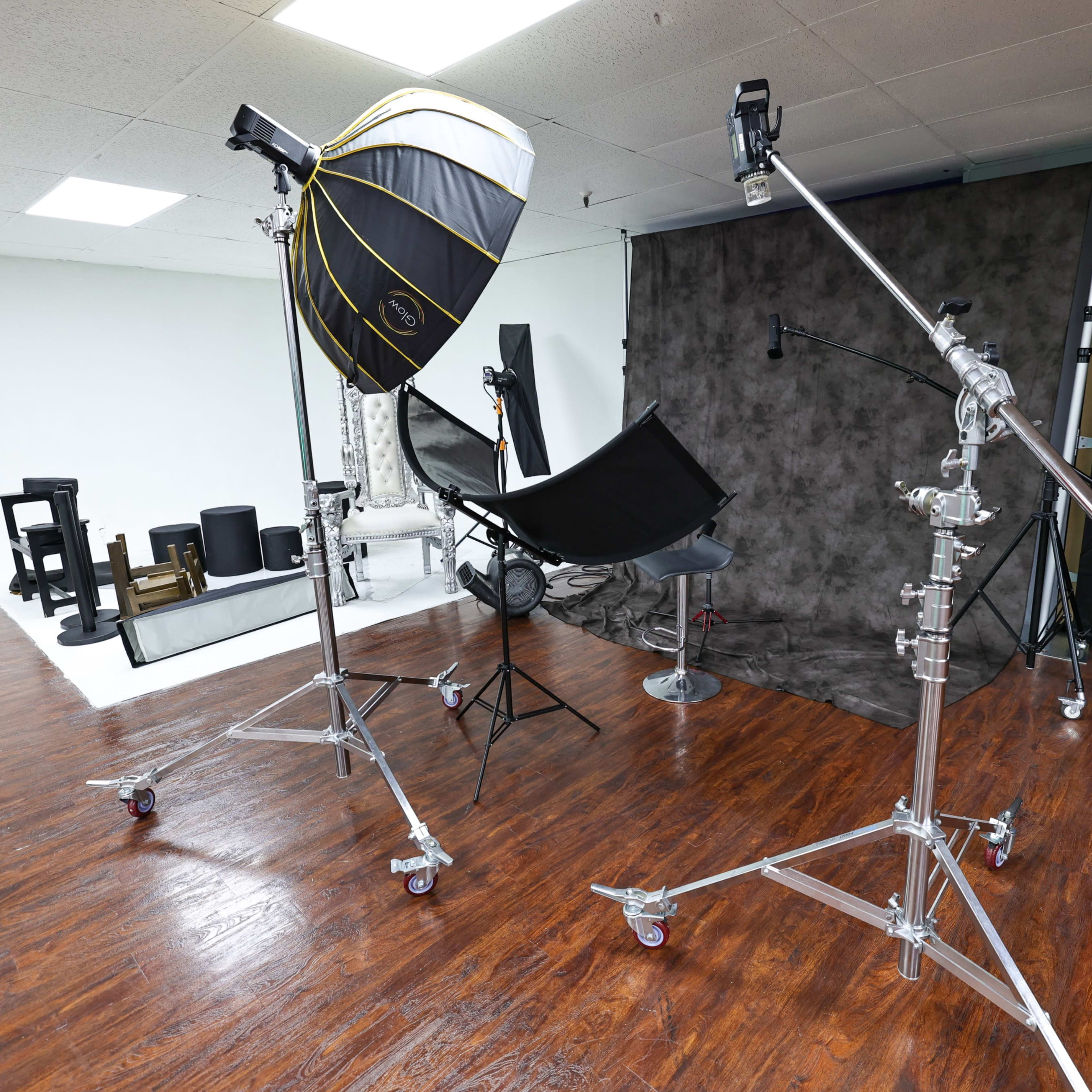 A photography studio setup with various lighting equipment and props arranged in a spacious area.