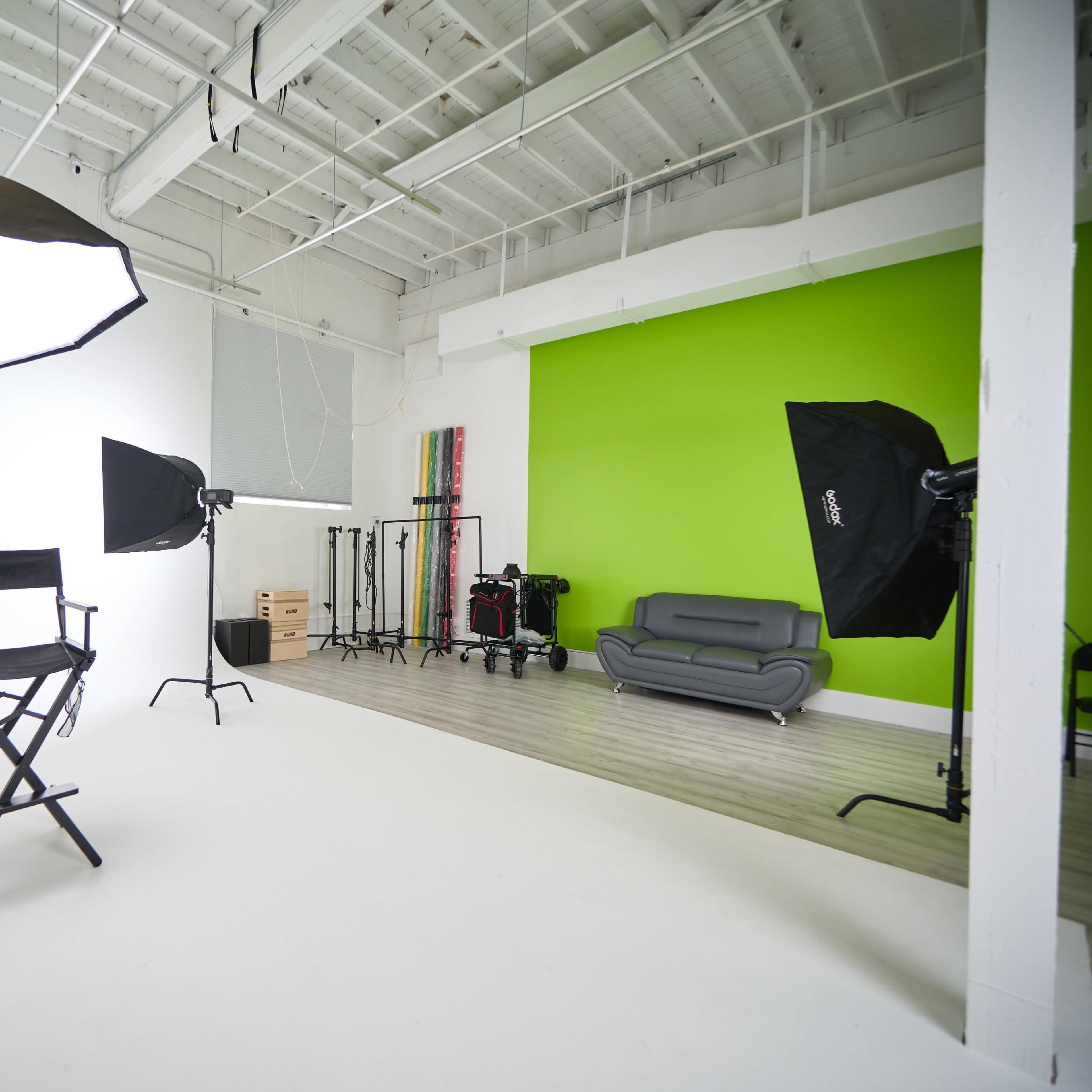 A photography studio with softbox lights, a director's chair, and a green accent wall.