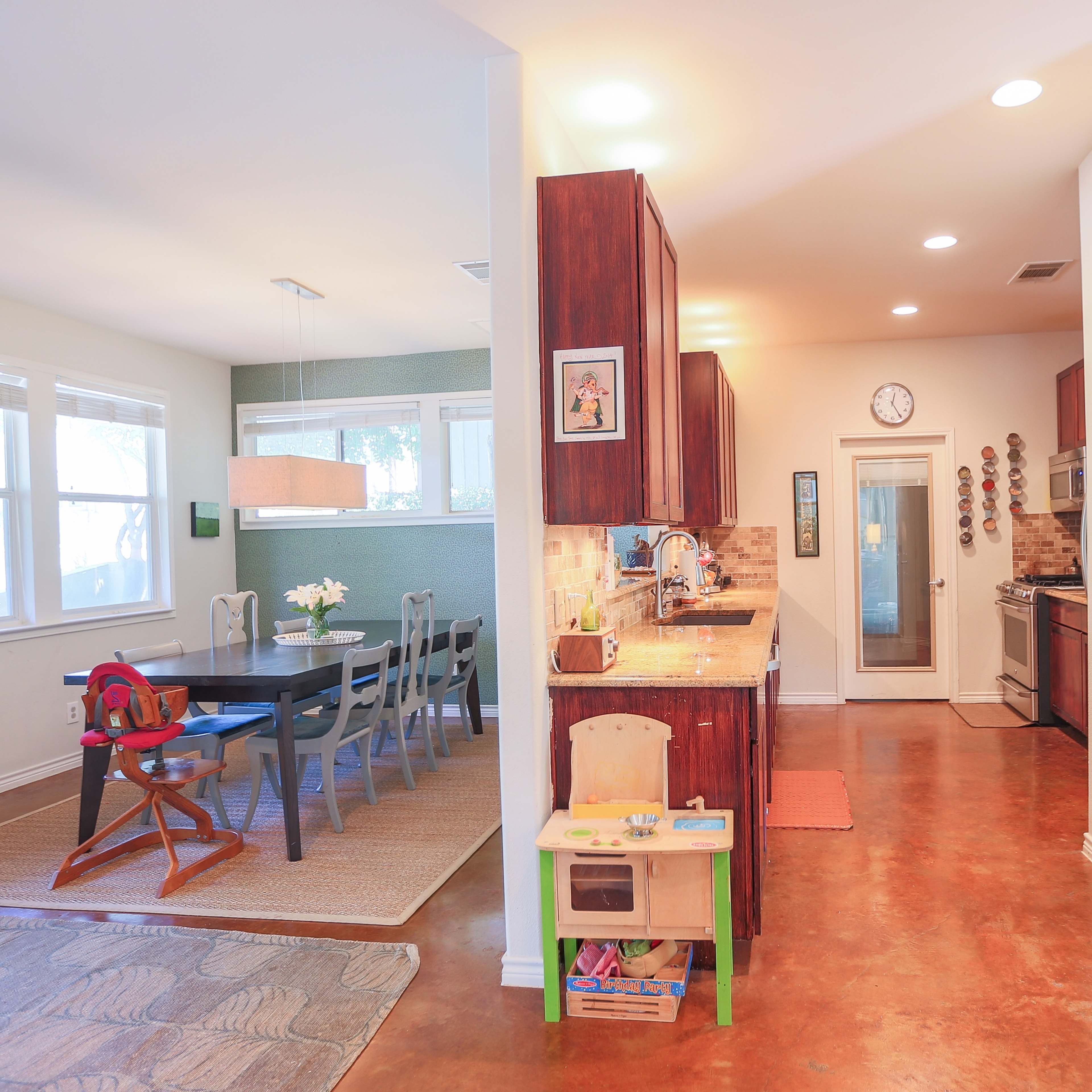 A spacious kitchen and dining area with wooden cabinets, a table set for six, and a play area with a small toy kitchen.