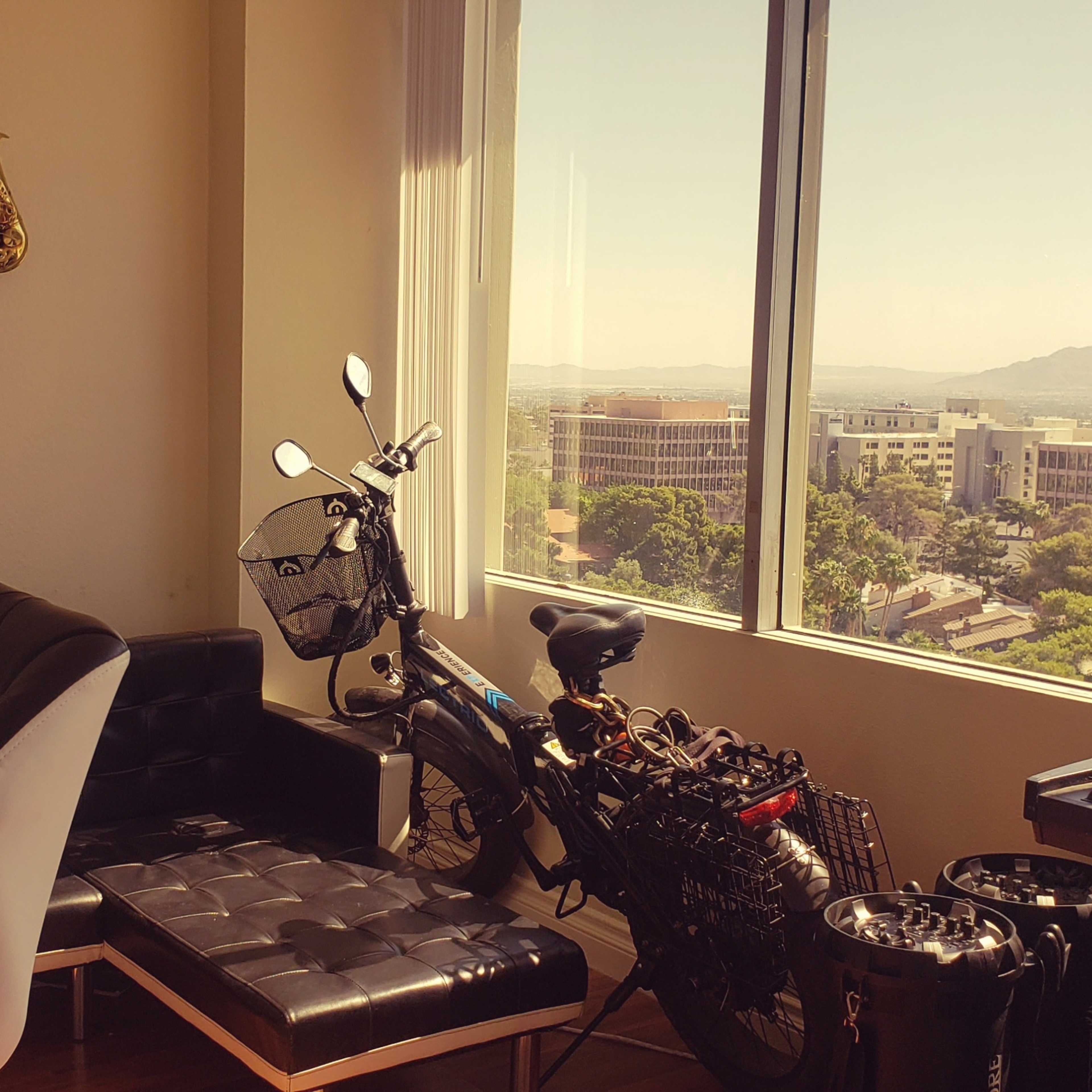 A modern room features a saxophone on the wall, a motorcycle parked beside a sleek sofa, and a keyboard on a side table with large windows showcasing a cityscape outside.