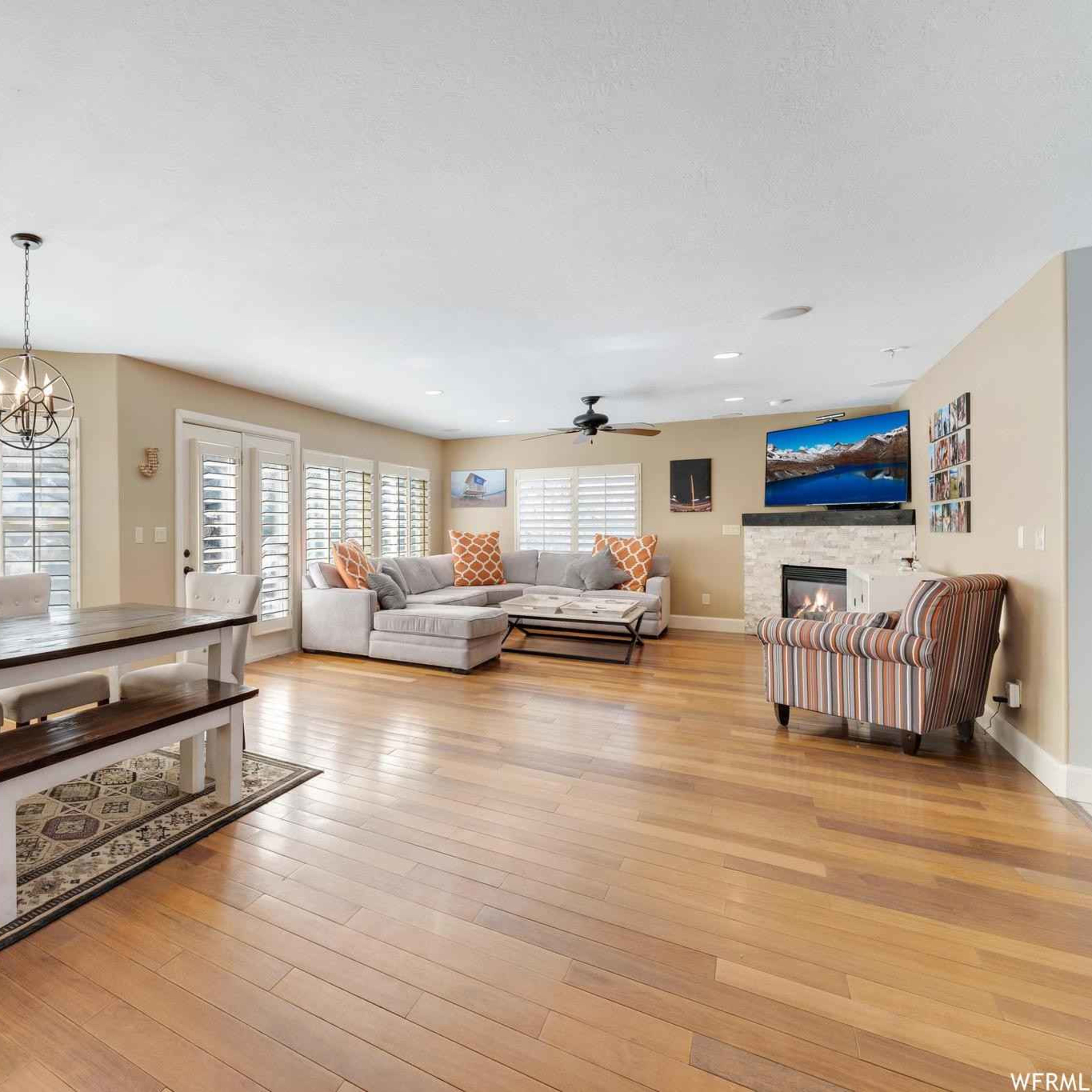 The spacious living and dining area features a large table, comfortable seating, and multiple windows with plantation shutters.