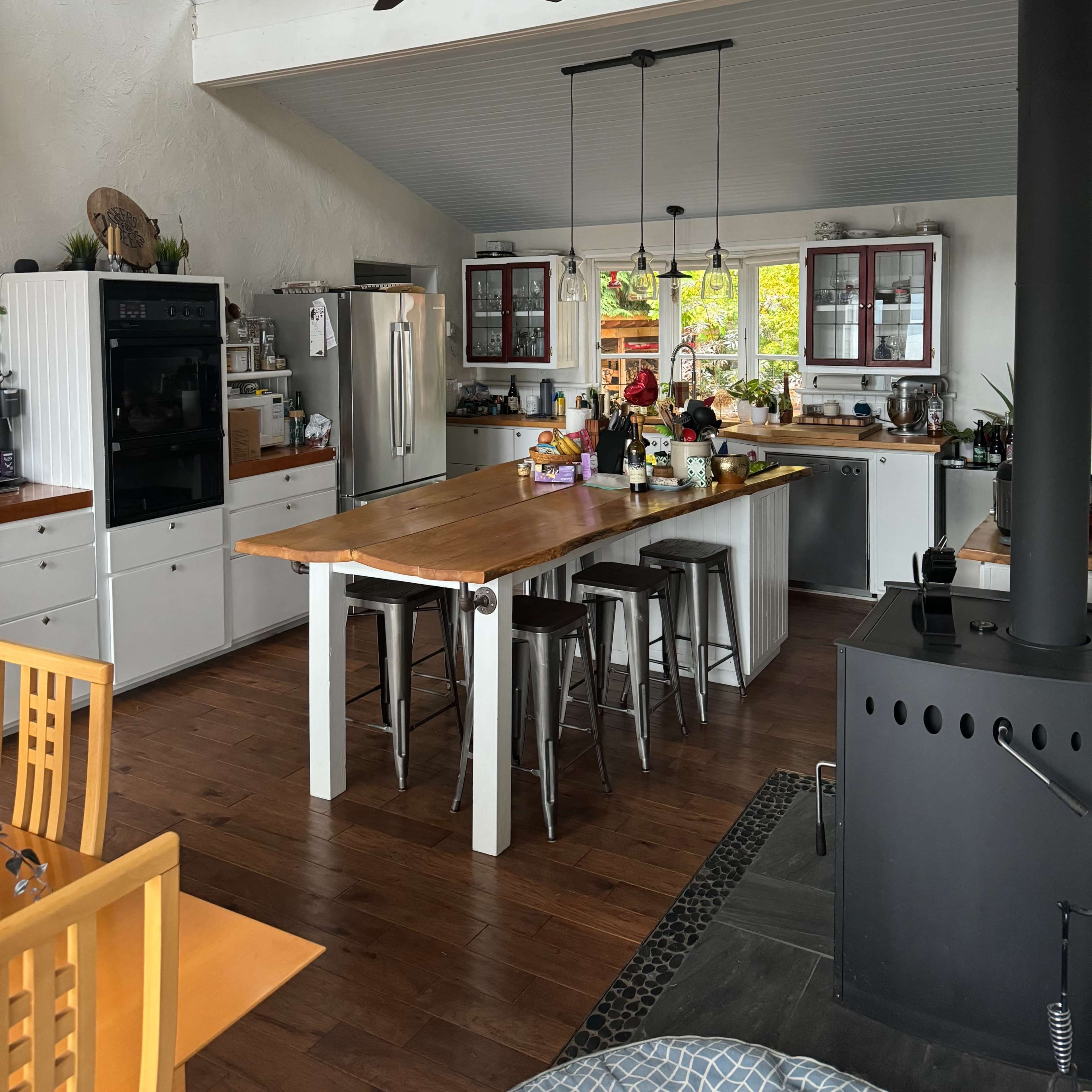 A spacious kitchen featuring a central island with bar stools, modern appliances, and large windows that provide natural light.