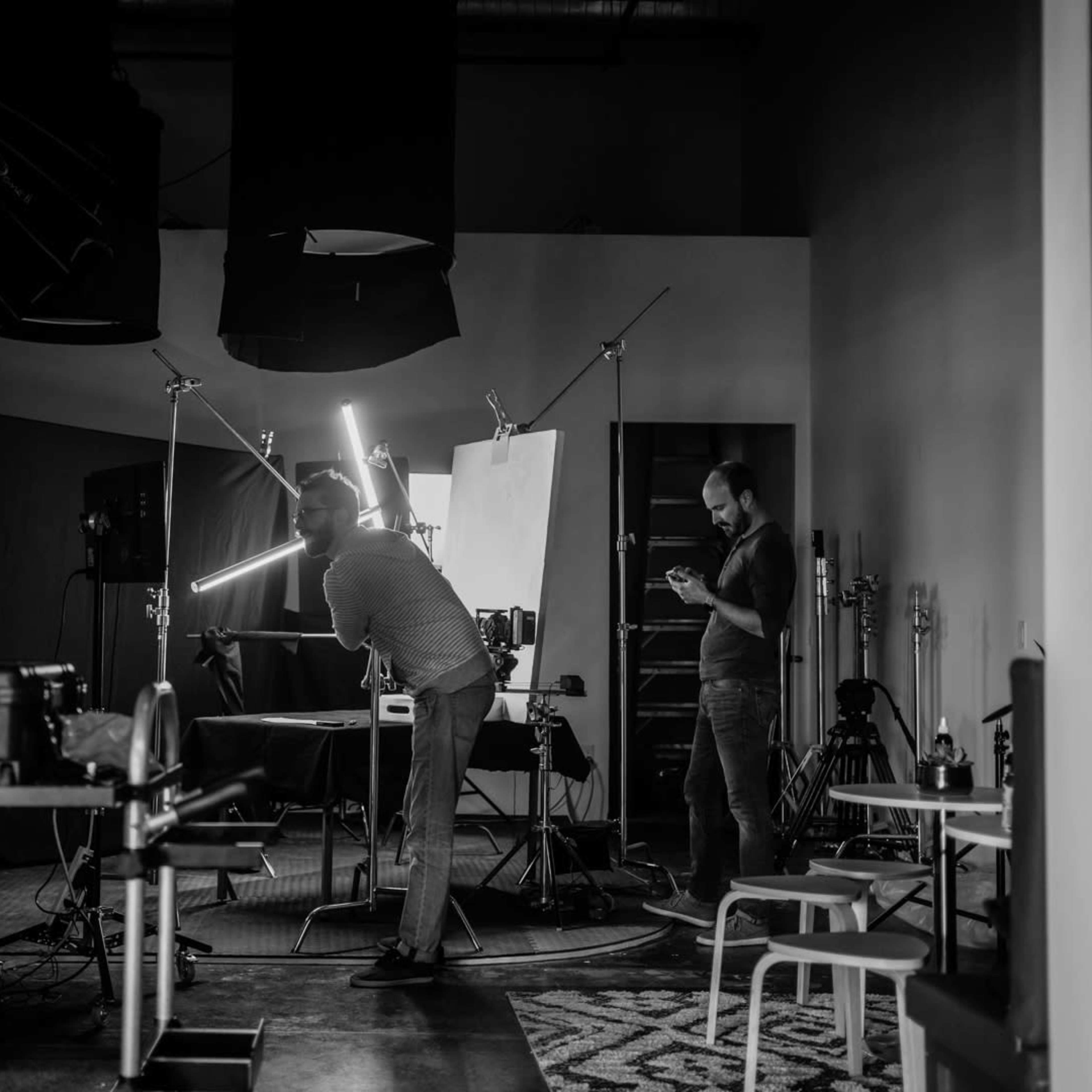 A photography studio is set up with various lighting equipment while two individuals prepare for a shoot.