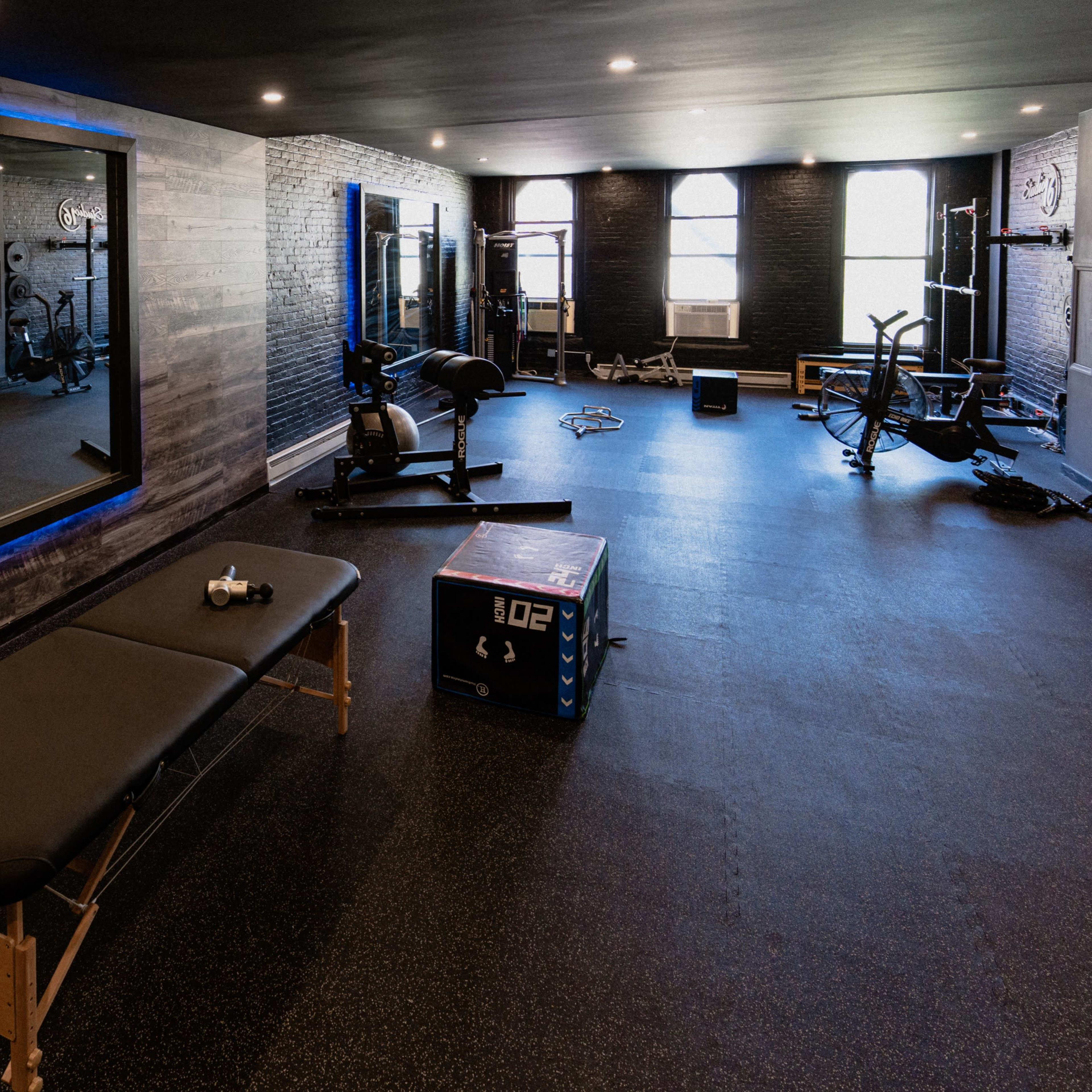A modern gym interior with equipment such as benches, weights, and exercise machines, complemented by a large wall mirror.
