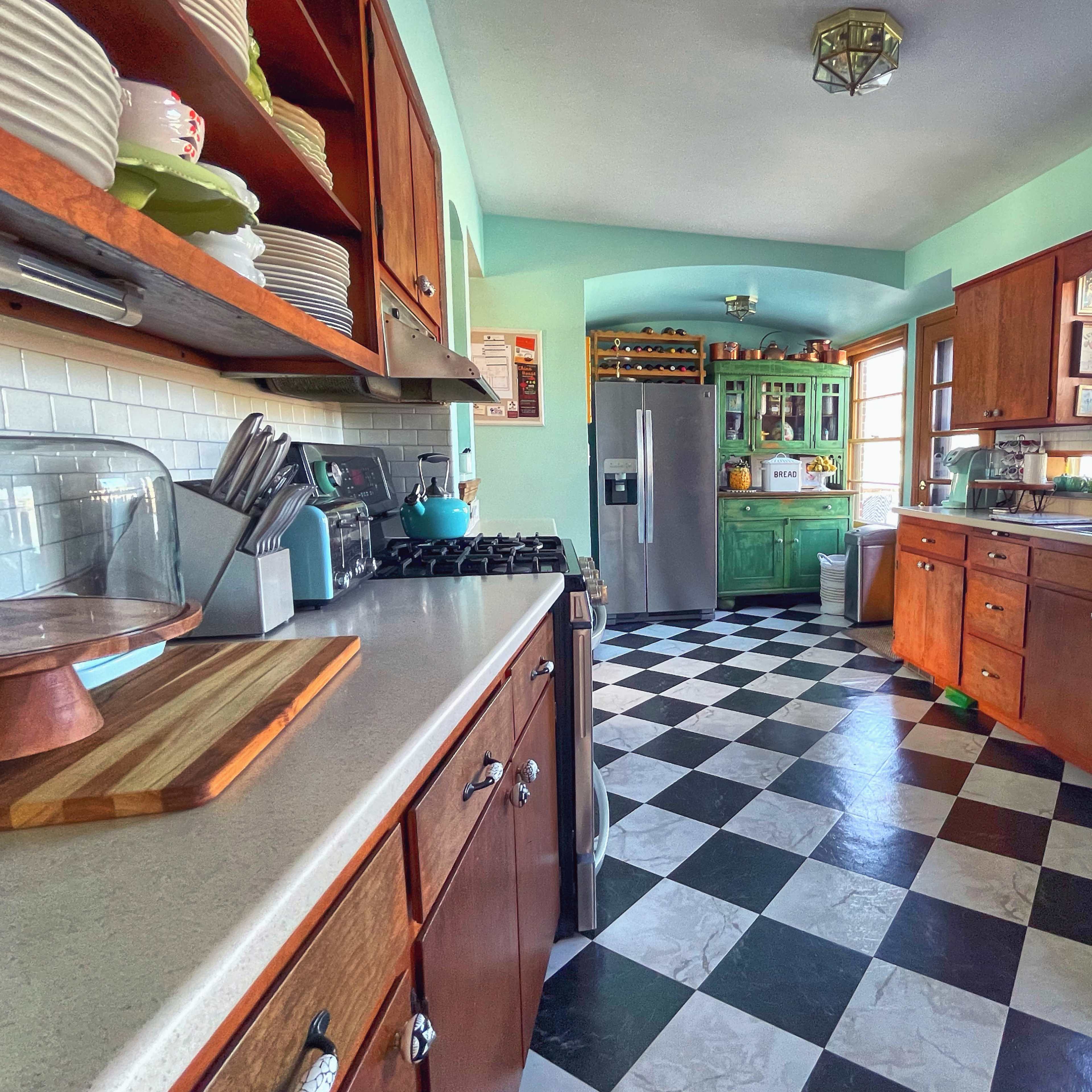A kitchen featuring a checkered black and white floor, wooden cabinets, and a combination of modern and rustic appliances.