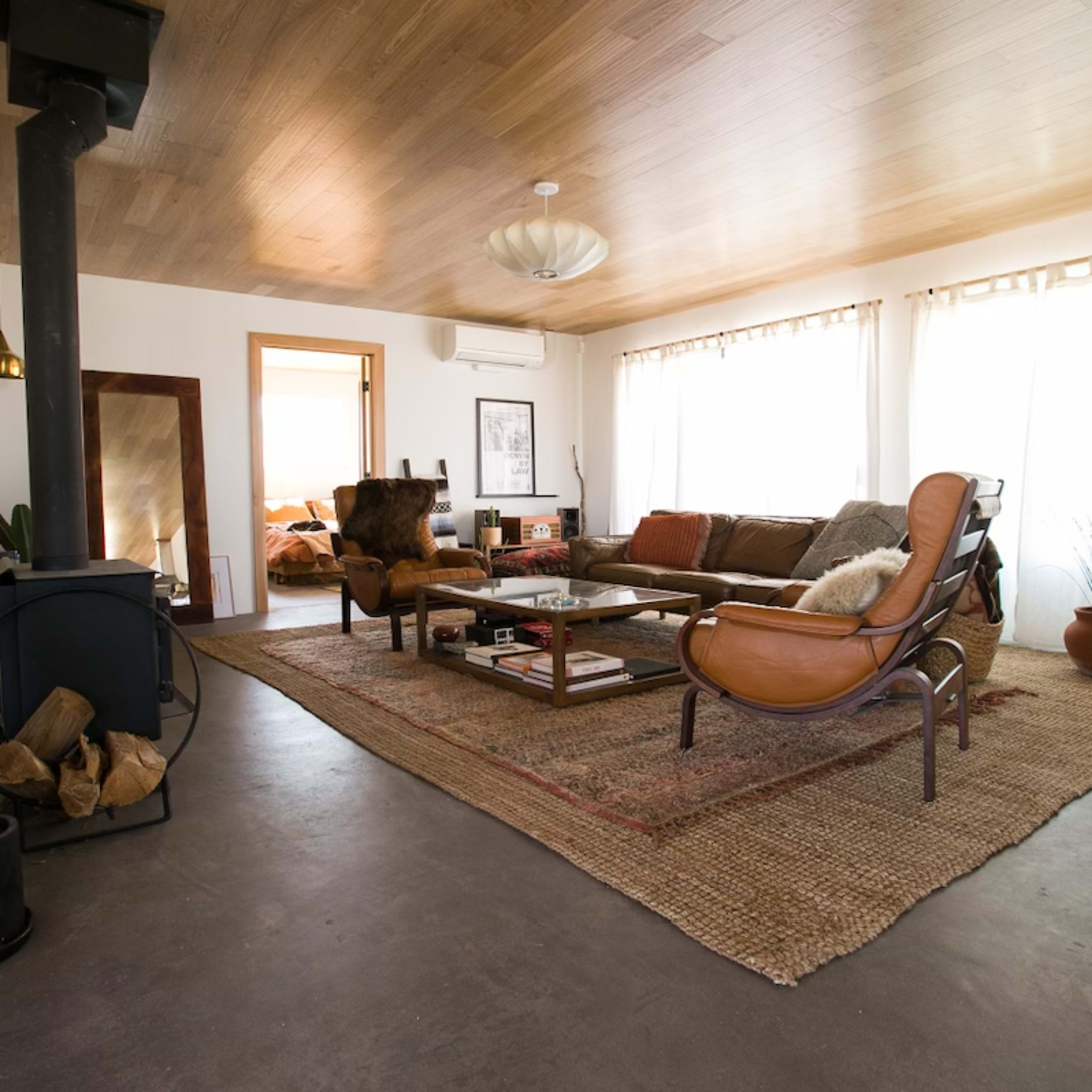 A spacious living room with a leather sofa, a wooden coffee table, and large windows allowing natural light to fill the space.