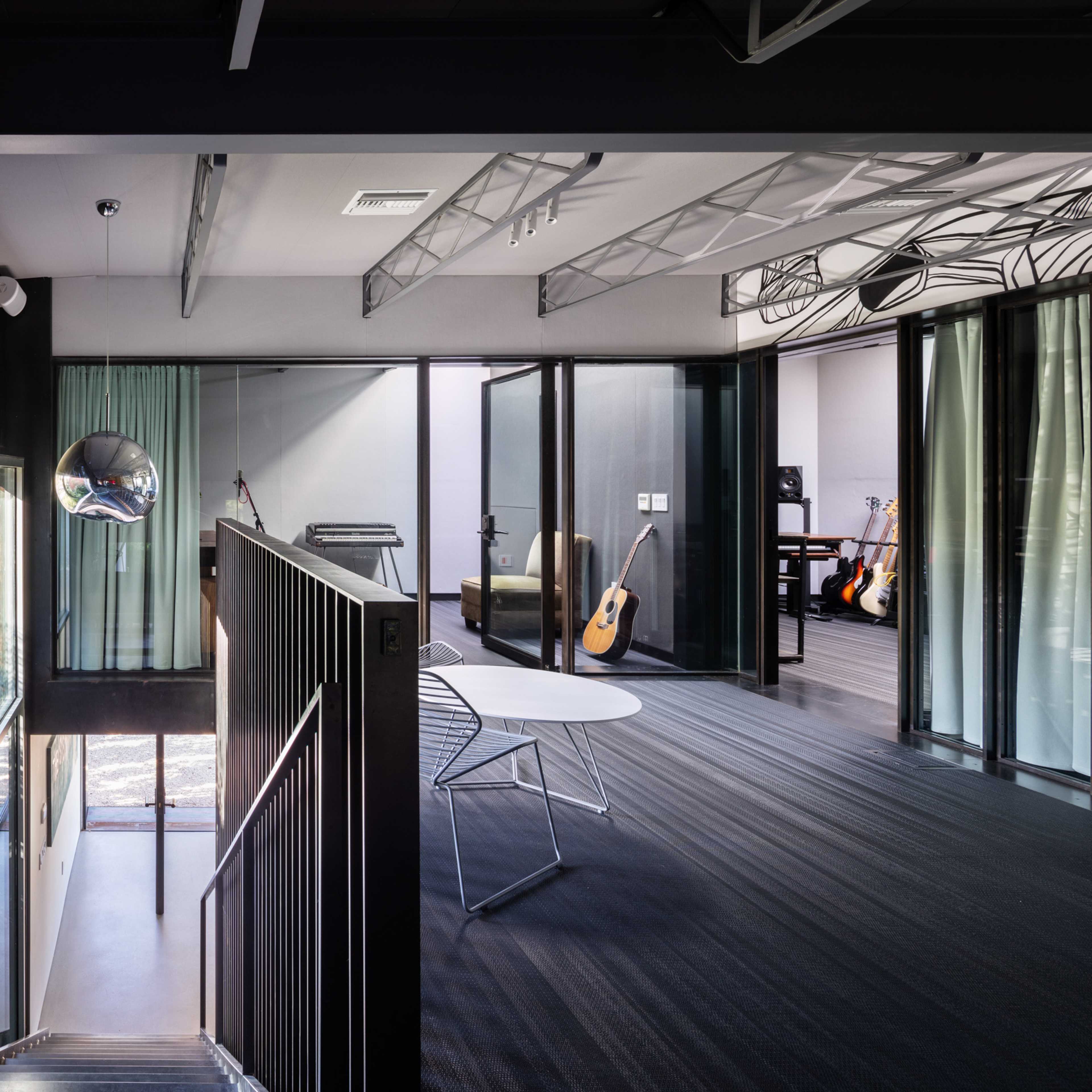 A modern interior space features a staircase leading to an open area with large glass windows and minimalist furnishings.