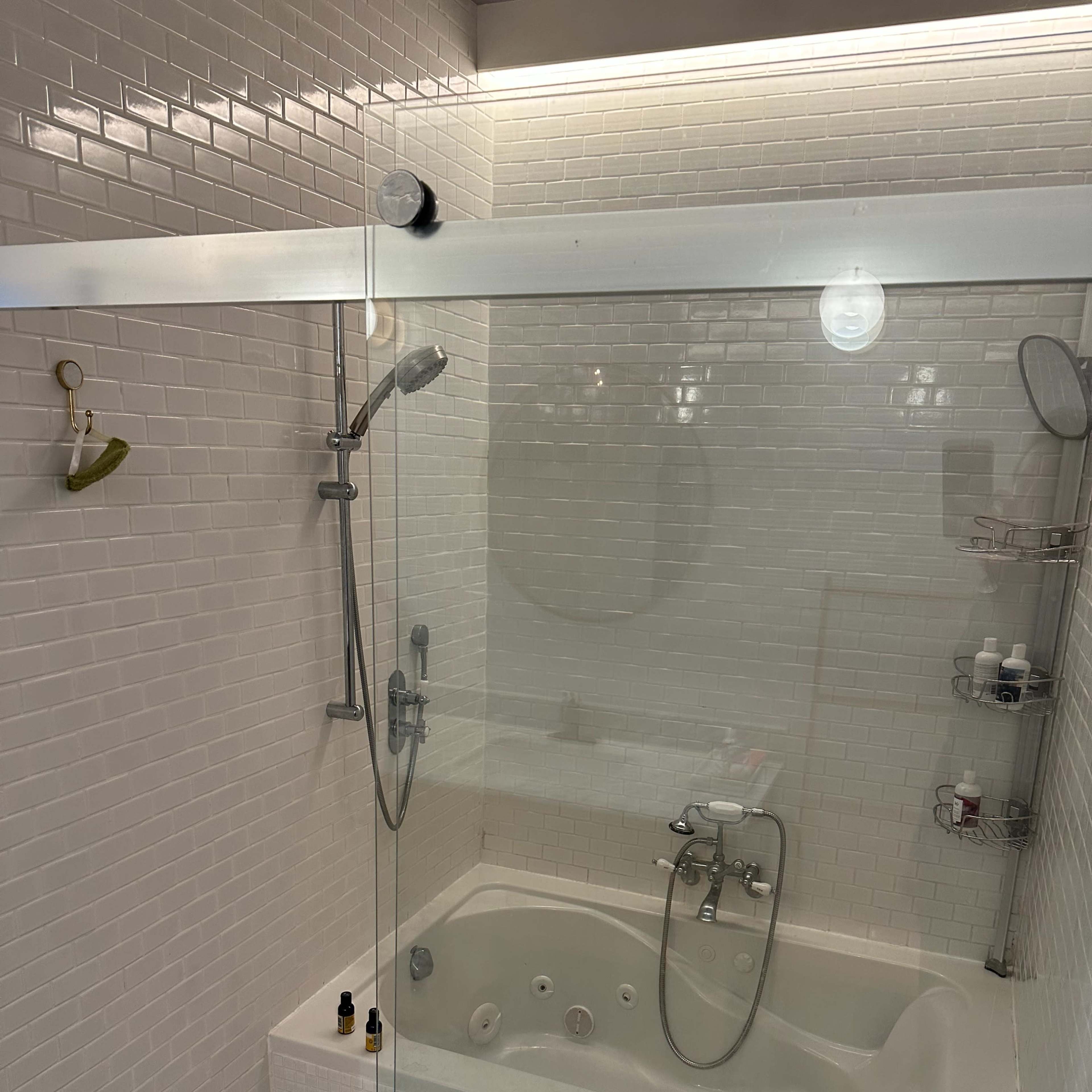A modern bathroom with a glass shower enclosure and a jetted bathtub surrounded by white tiles.