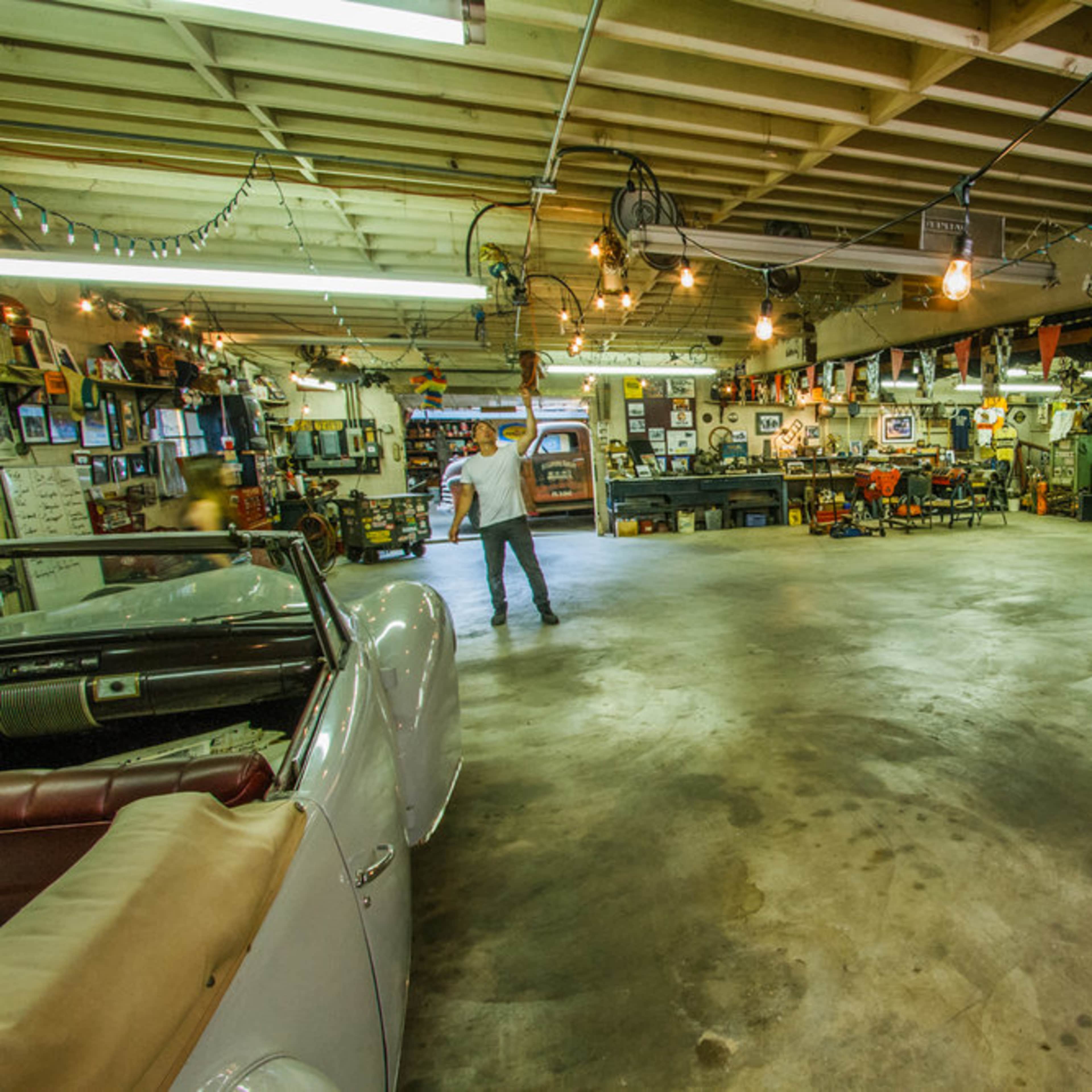 A spacious garage filled with classic cars, memorabilia, and a well-lit interior showcasing various automotive decorations.