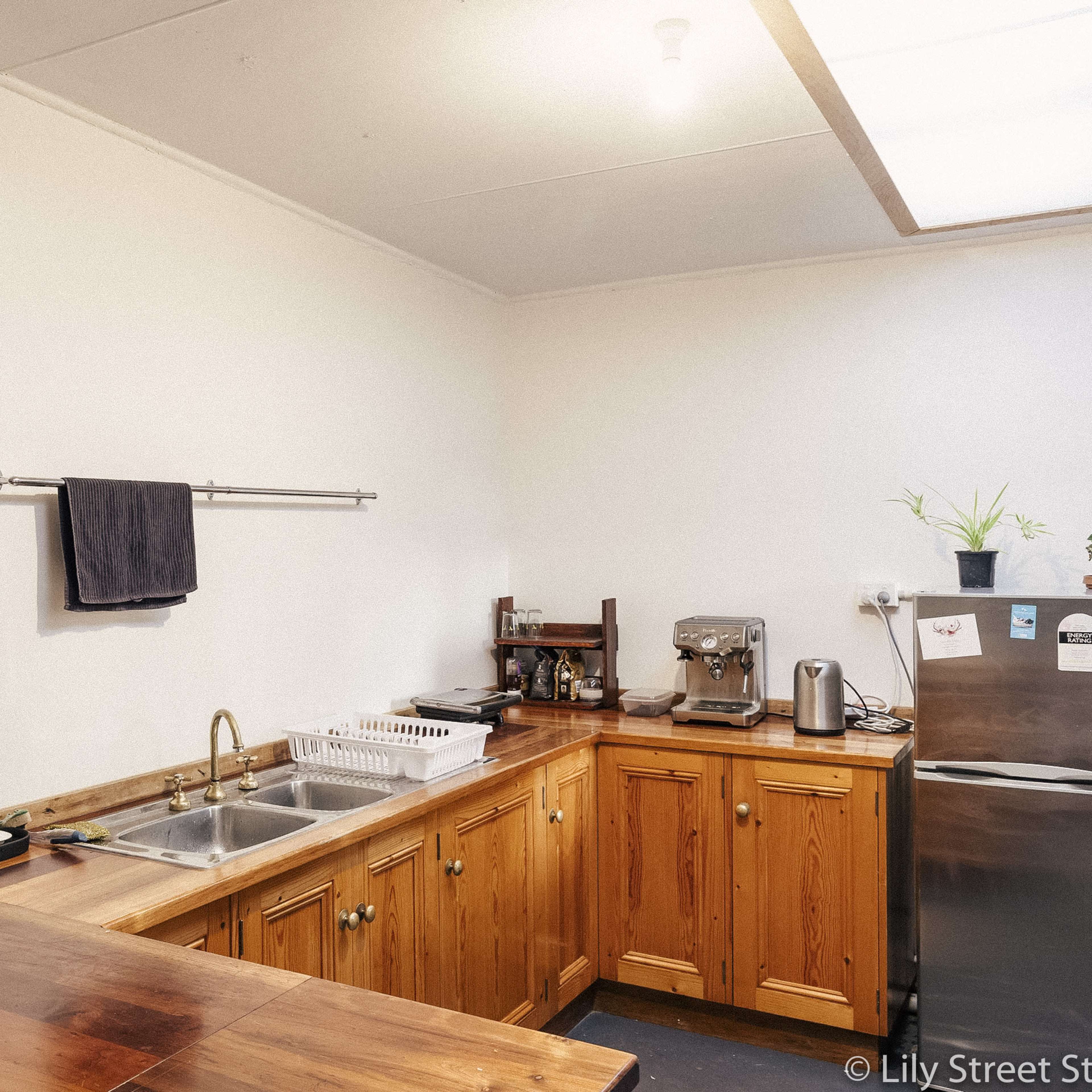 A kitchen with wooden cabinets, a stainless steel refrigerator, a microwave, a sink, and a countertop.