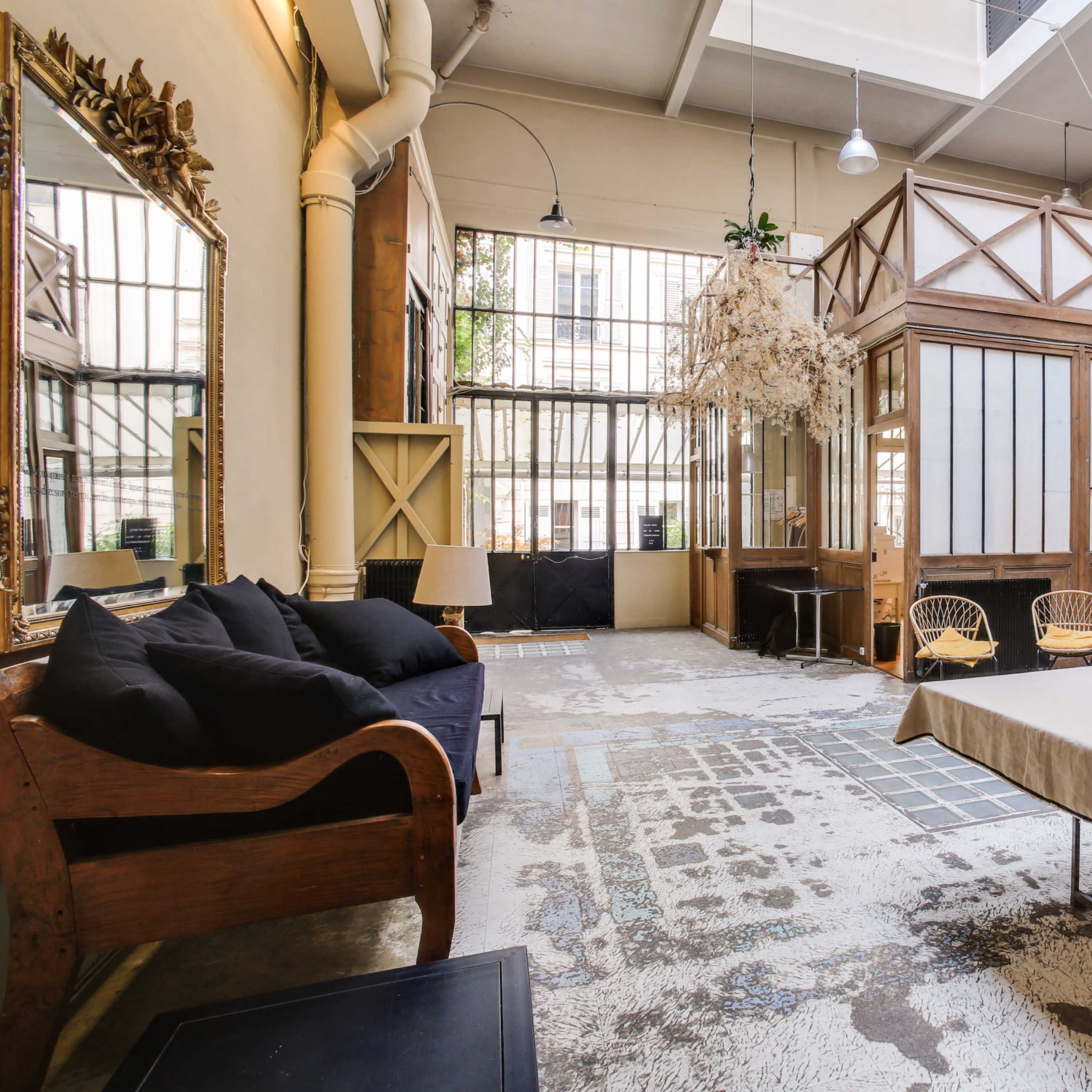 An open, spacious interior with wooden details, large windows, and a minimalist furniture arrangement, including a couch and a table.