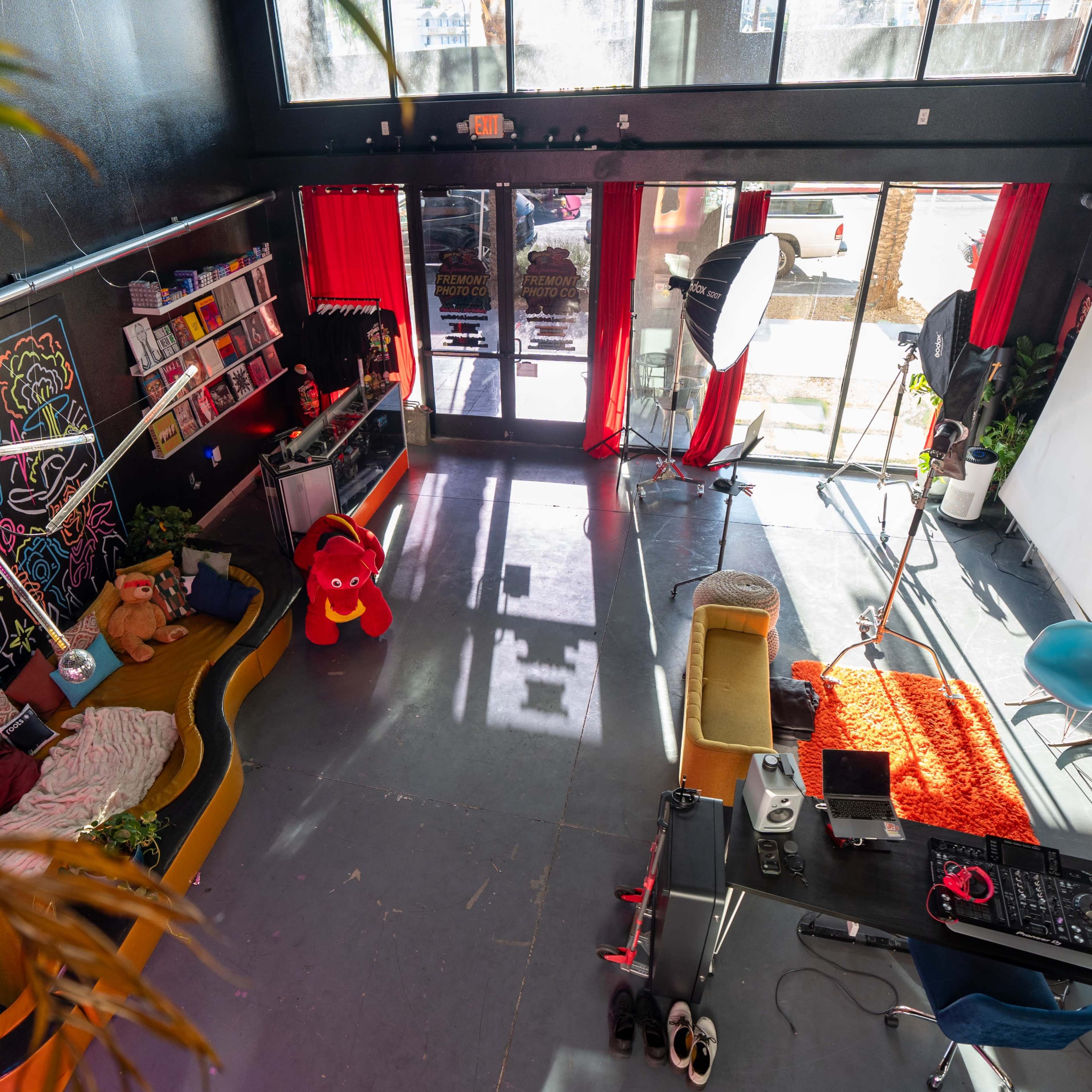 A brightly colored studio space with a large mural, seating areas, and equipment for a photo shoot.