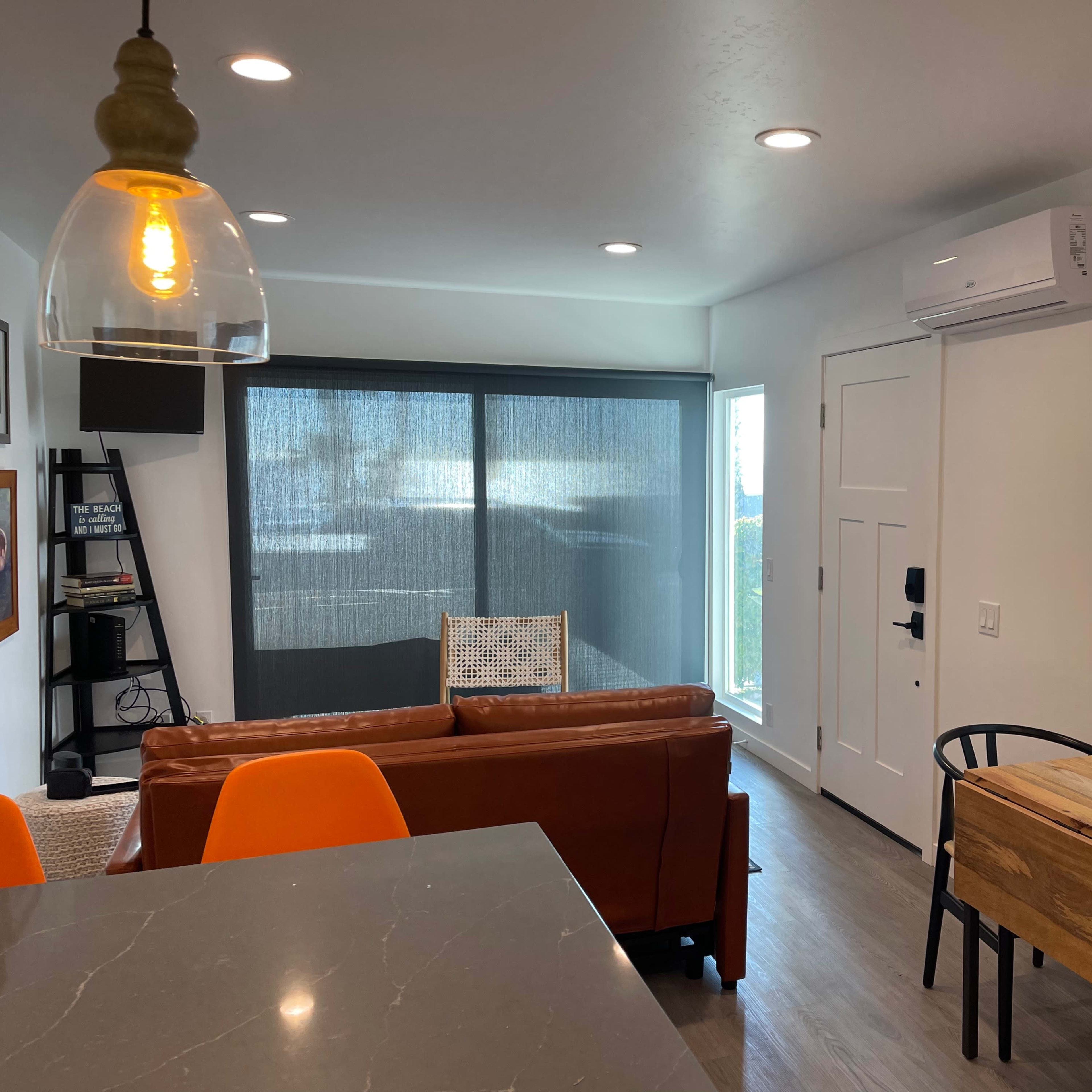 A modern living space featuring a brown sofa, a wooden dining table with black chairs, and a large window with a view.