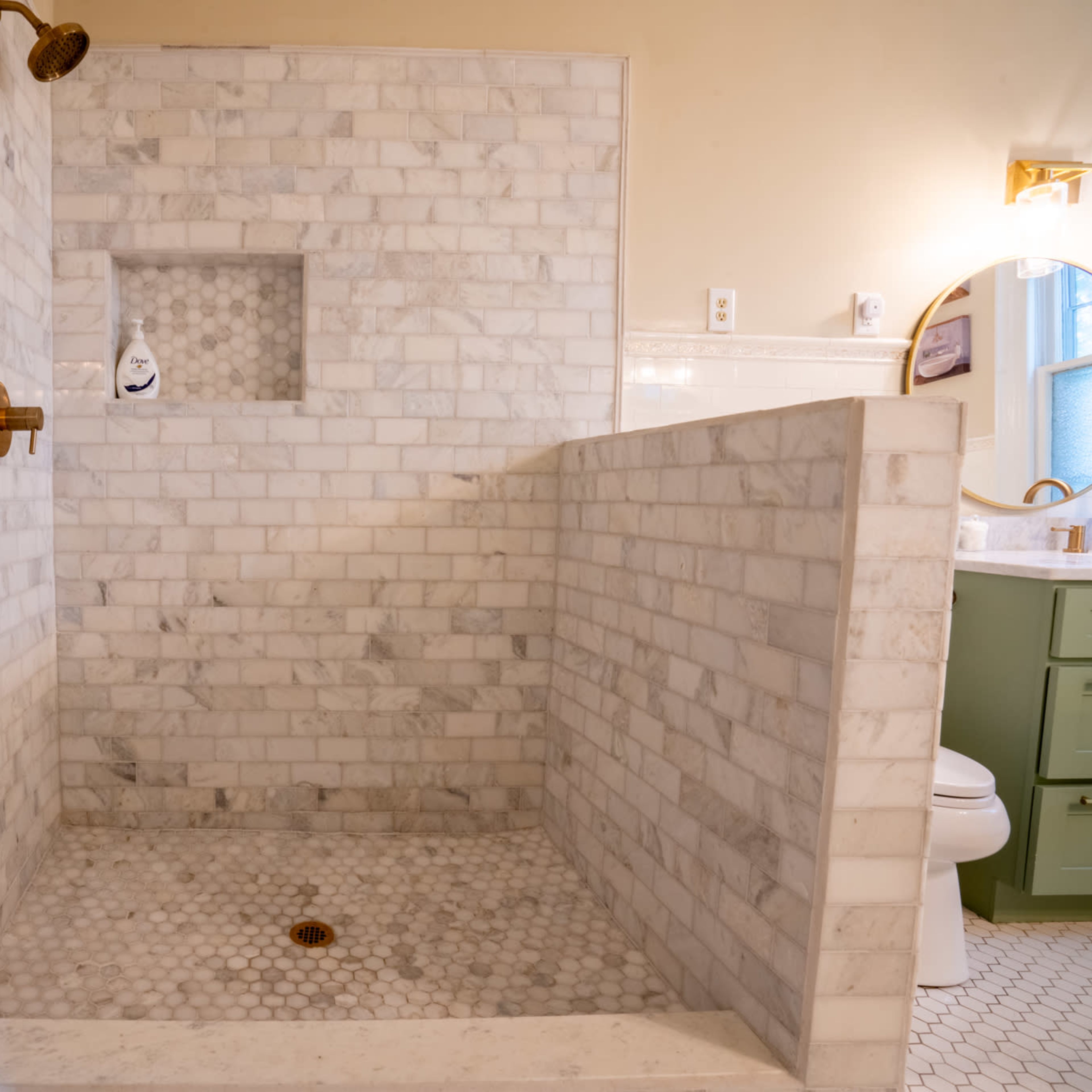 A tiled shower area with marble walls and a hexagonal tiled floor.