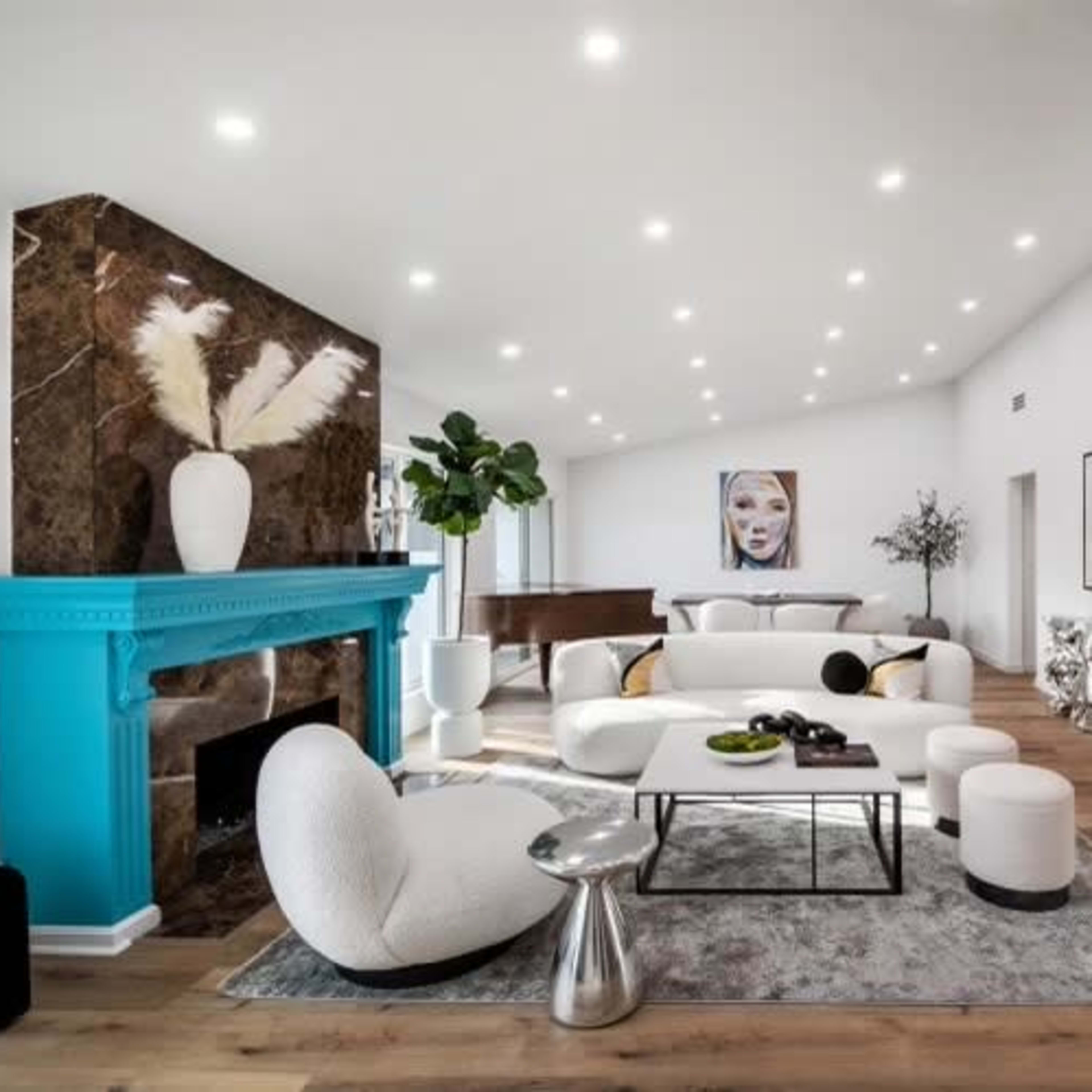 A modern living room features a white sectional sofa, a turquoise fireplace, and a decorative plant next to a large artwork.