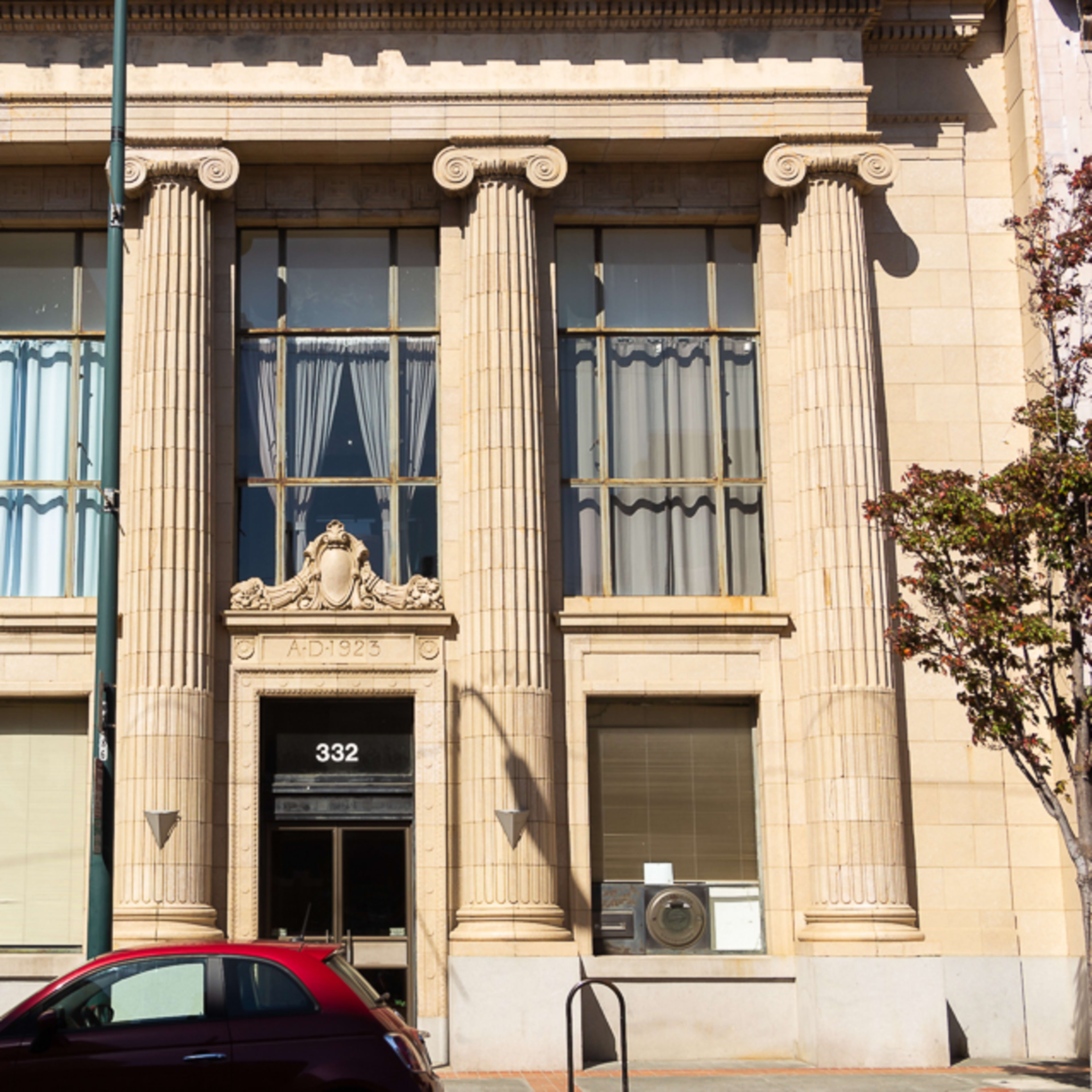 A classical-style building with tall columns, large windows, and a decorative facade, located at 332.
