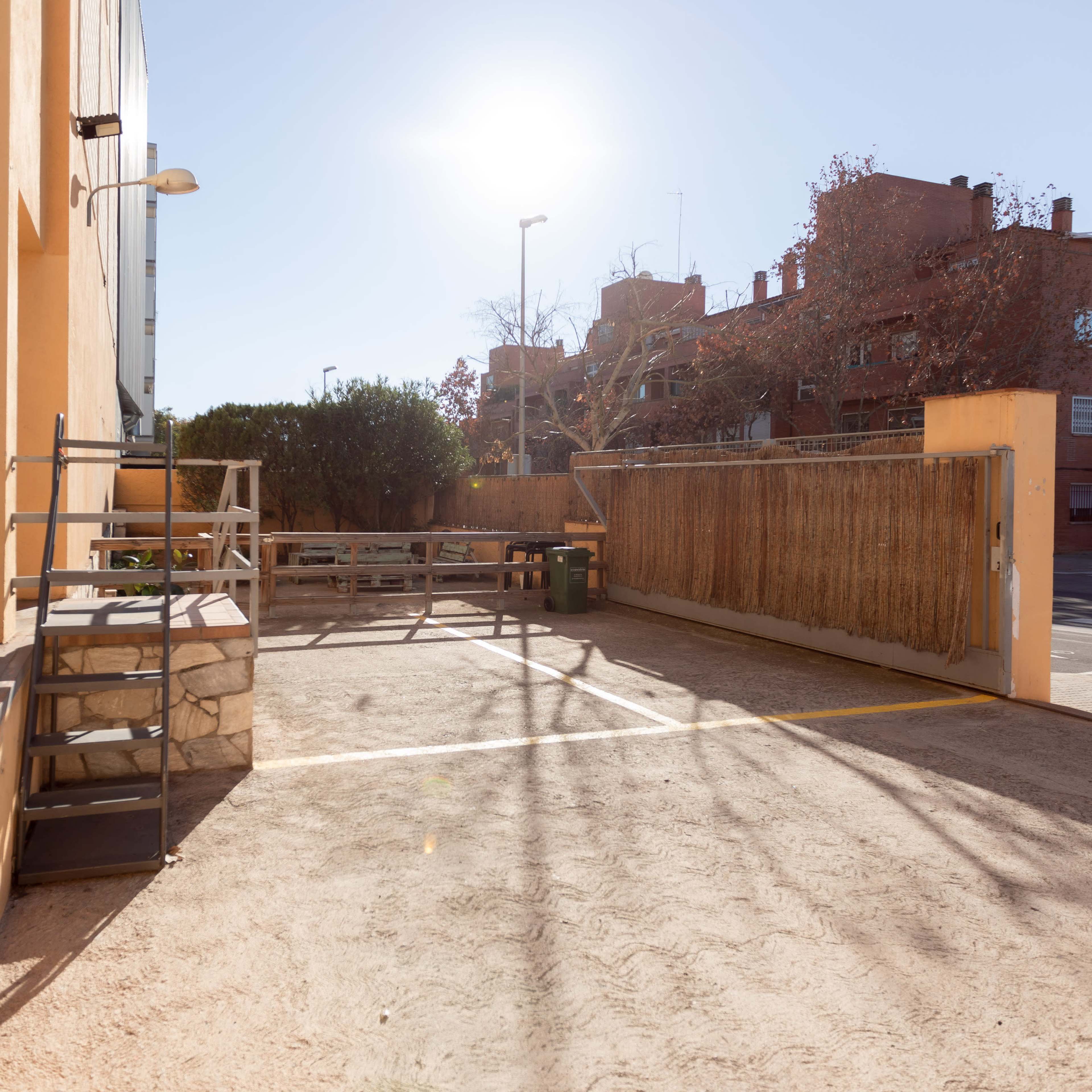 A sunny, unpaved area with a wooden fence and steps leading to a small platform.