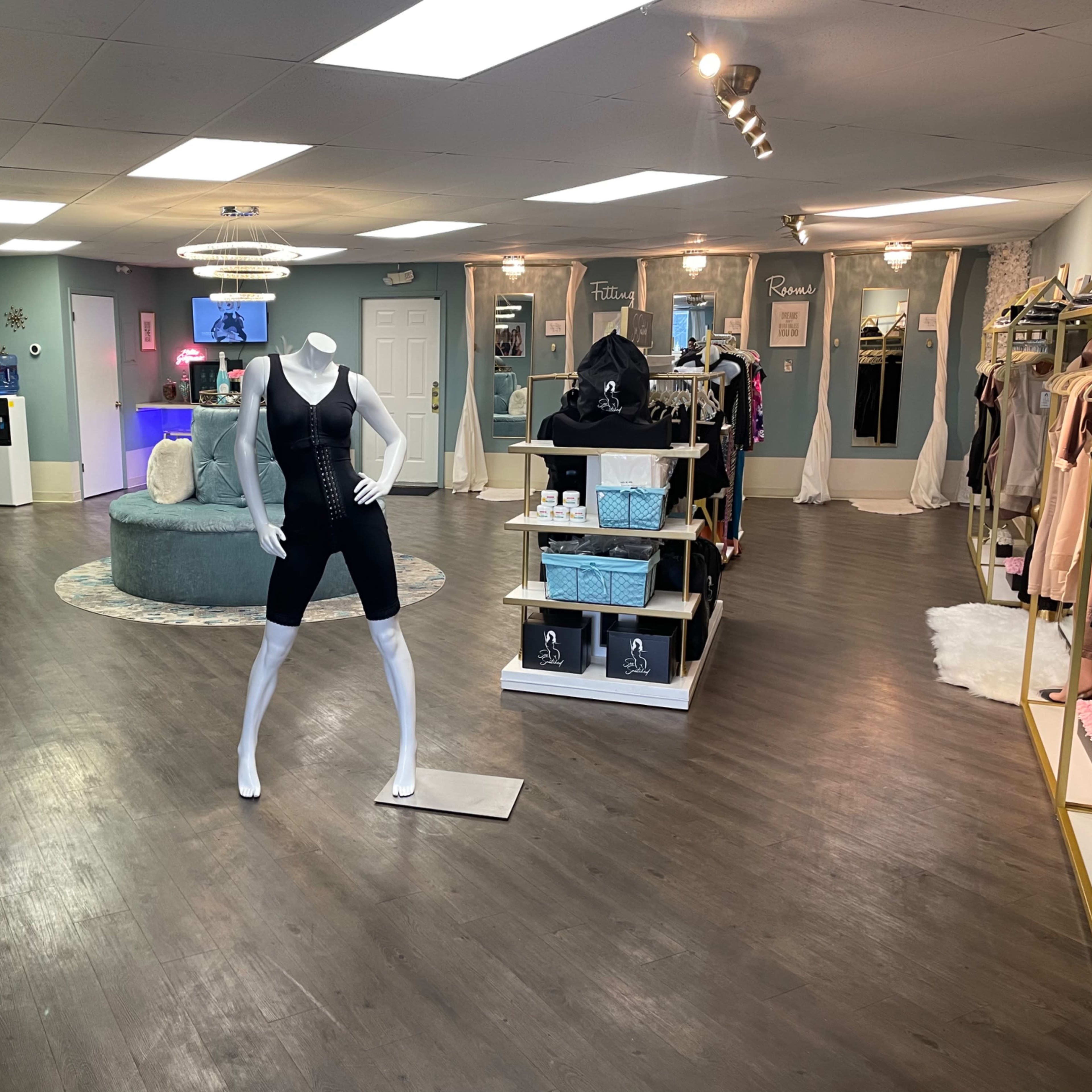An interior of a boutique featuring a mannequin dressed in activewear, surrounded by clothing racks and displays on wooden flooring.