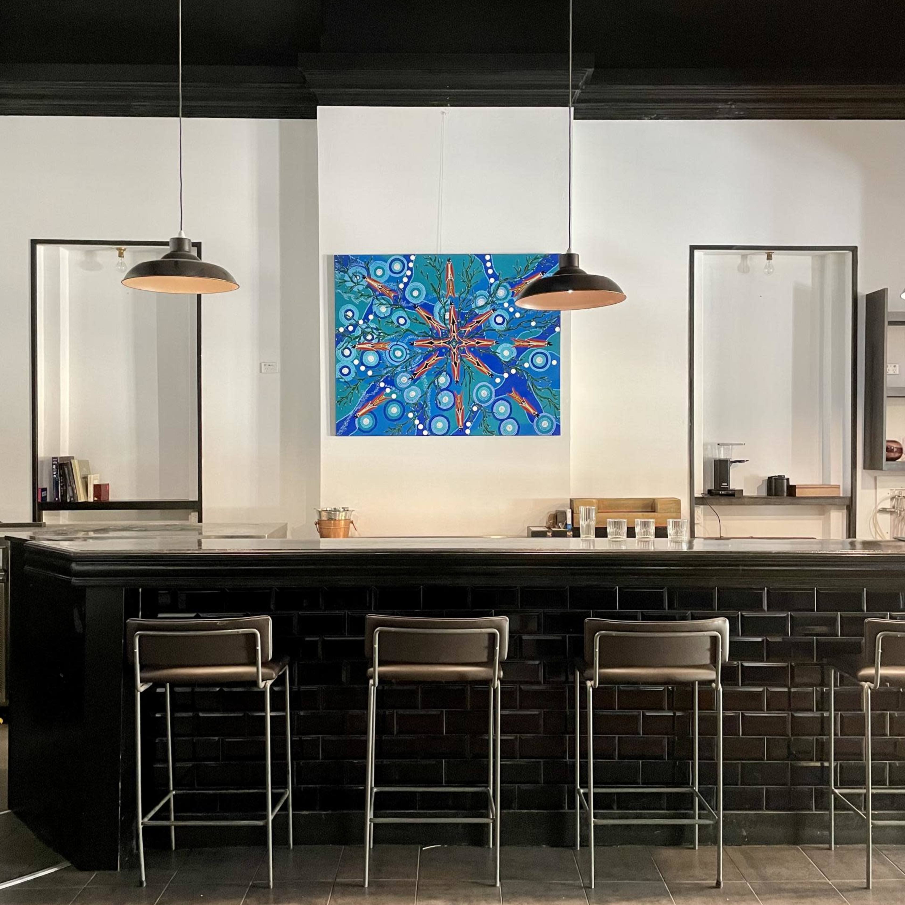 A modern bar area with a black countertop, metal stools, and a colorful abstract painting on the wall behind it.