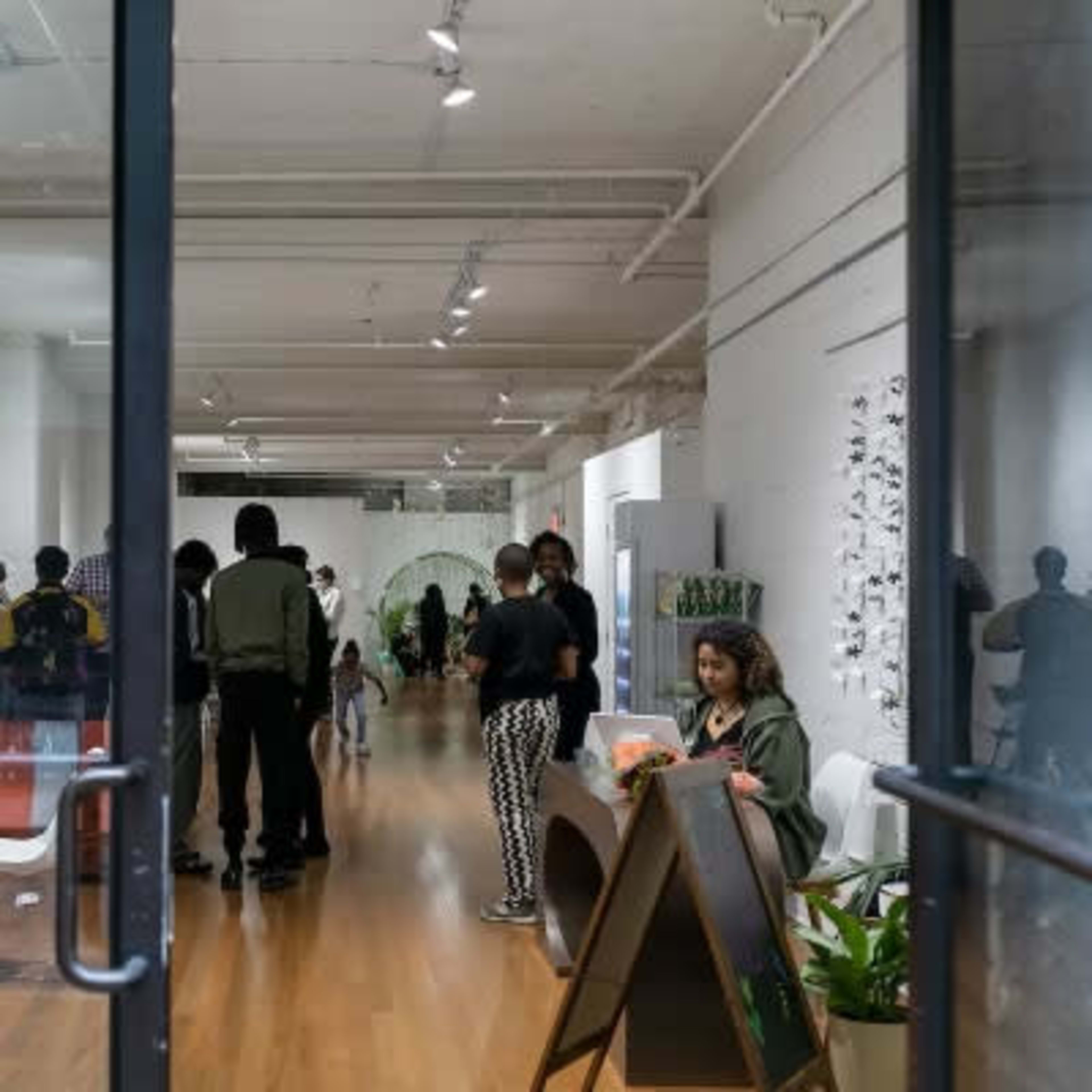 A bright, modern indoor space with a large window displaying the "GG & POP" logo and several people gathered inside, engaged in conversation.