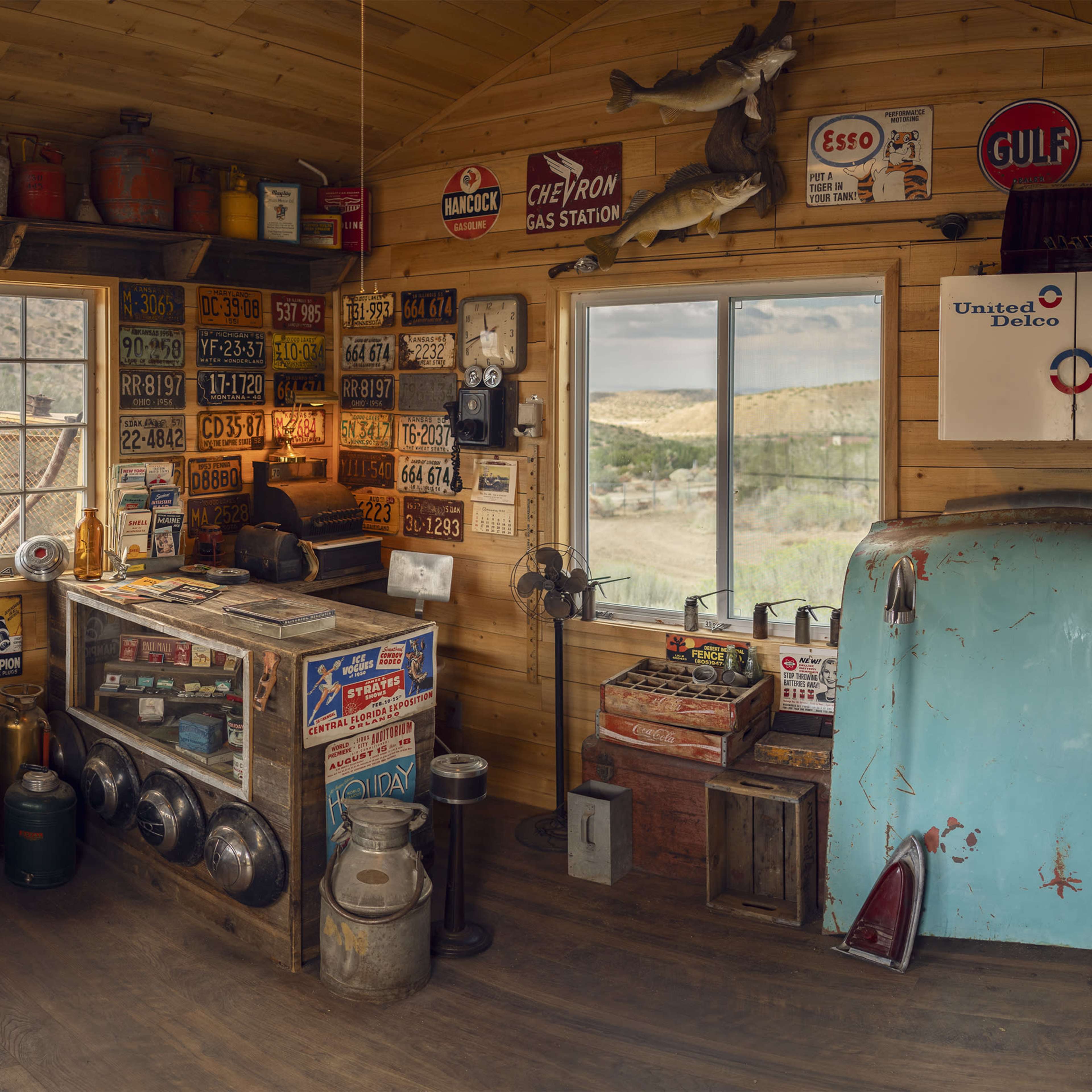 The interior of a rustic gas station maintenance shop filled with vintage equipment, cans, and signs mounted on the wooden walls.