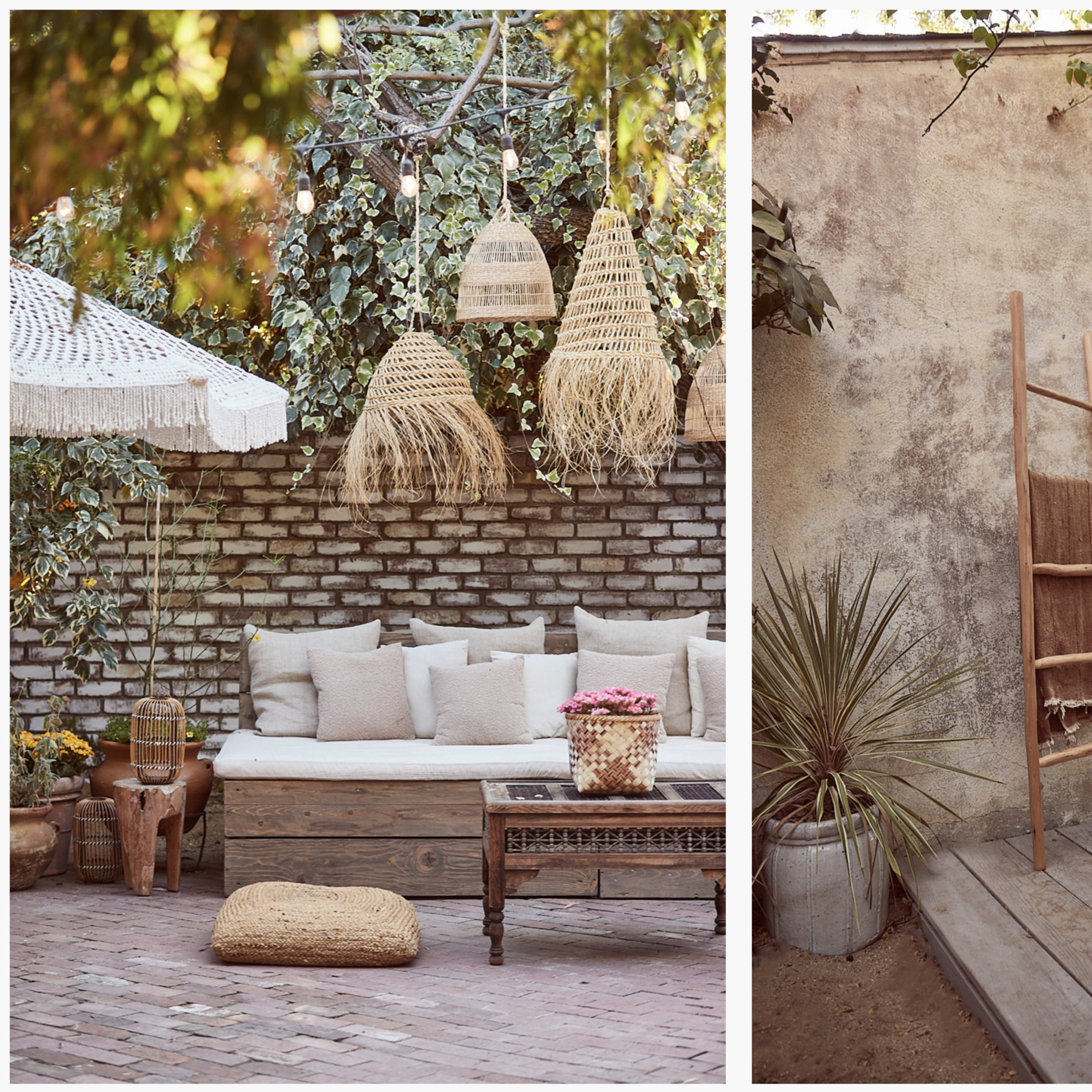 A cozy outdoor seating area with a cushioned bench, woven decor, and a wooden ladder against a textured wall, surrounded by plants.