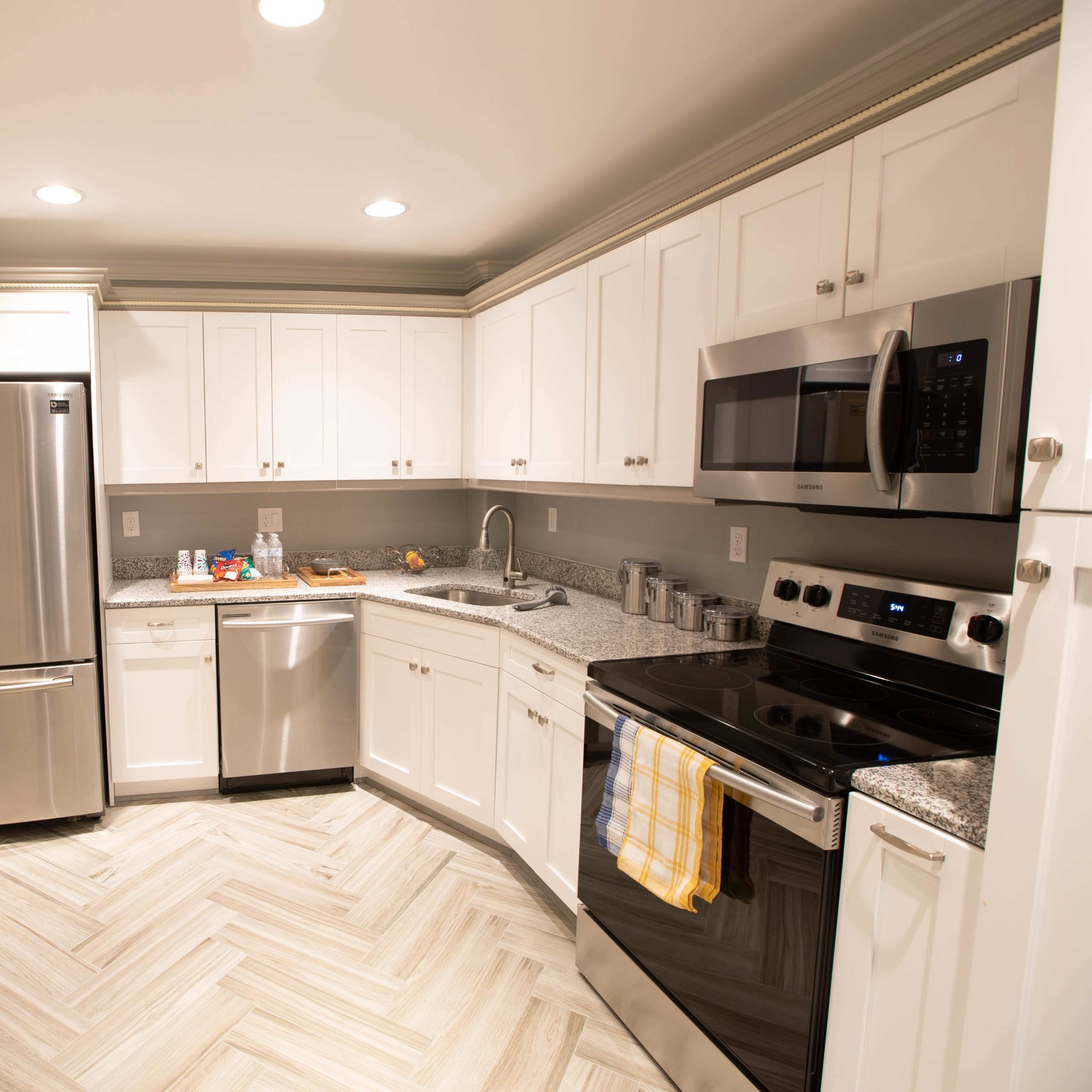 A modern kitchen with white cabinets, stainless steel appliances, and a light gray and yellow color scheme.
