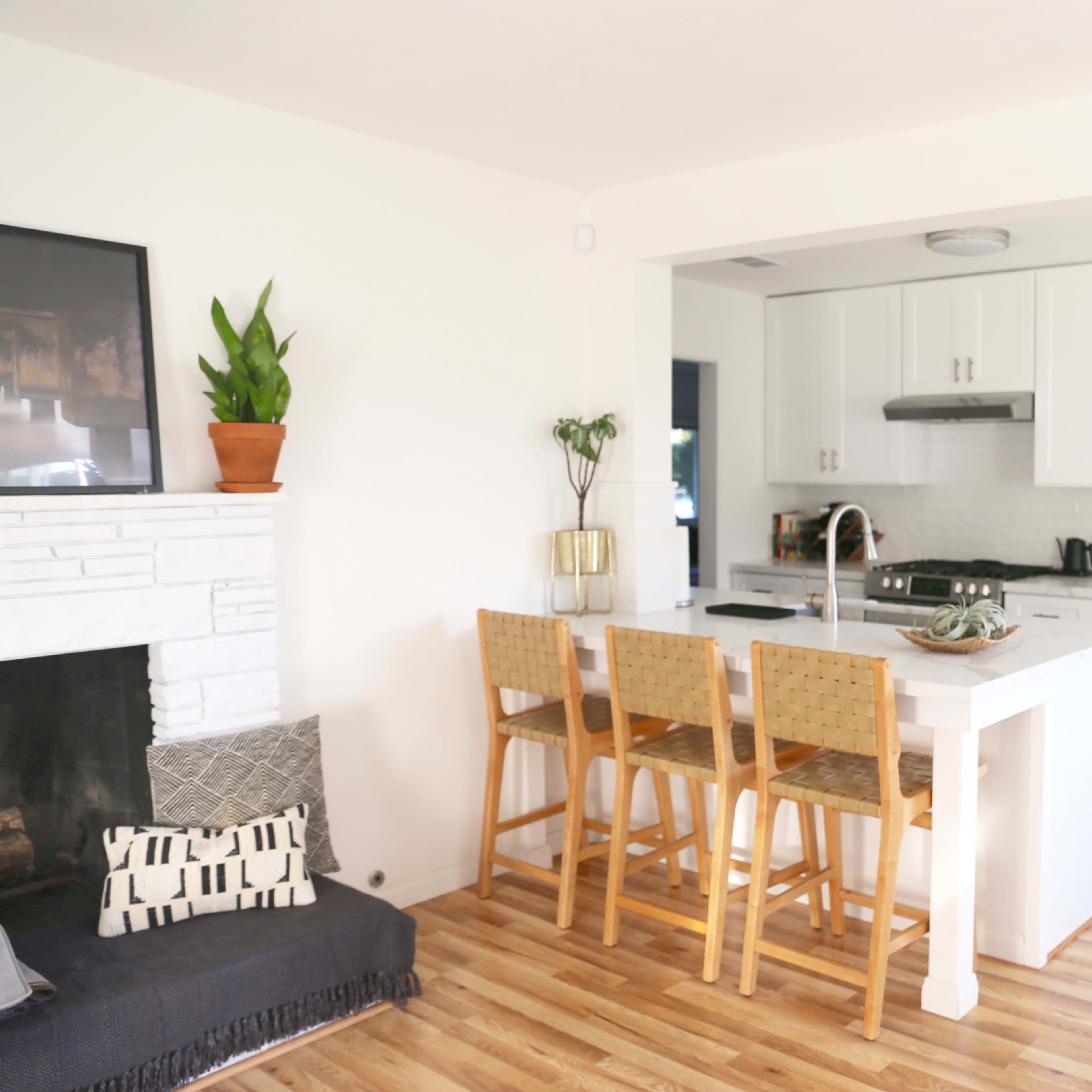 The kitchen features white cabinetry, a large island with bar stools, and wooden flooring.