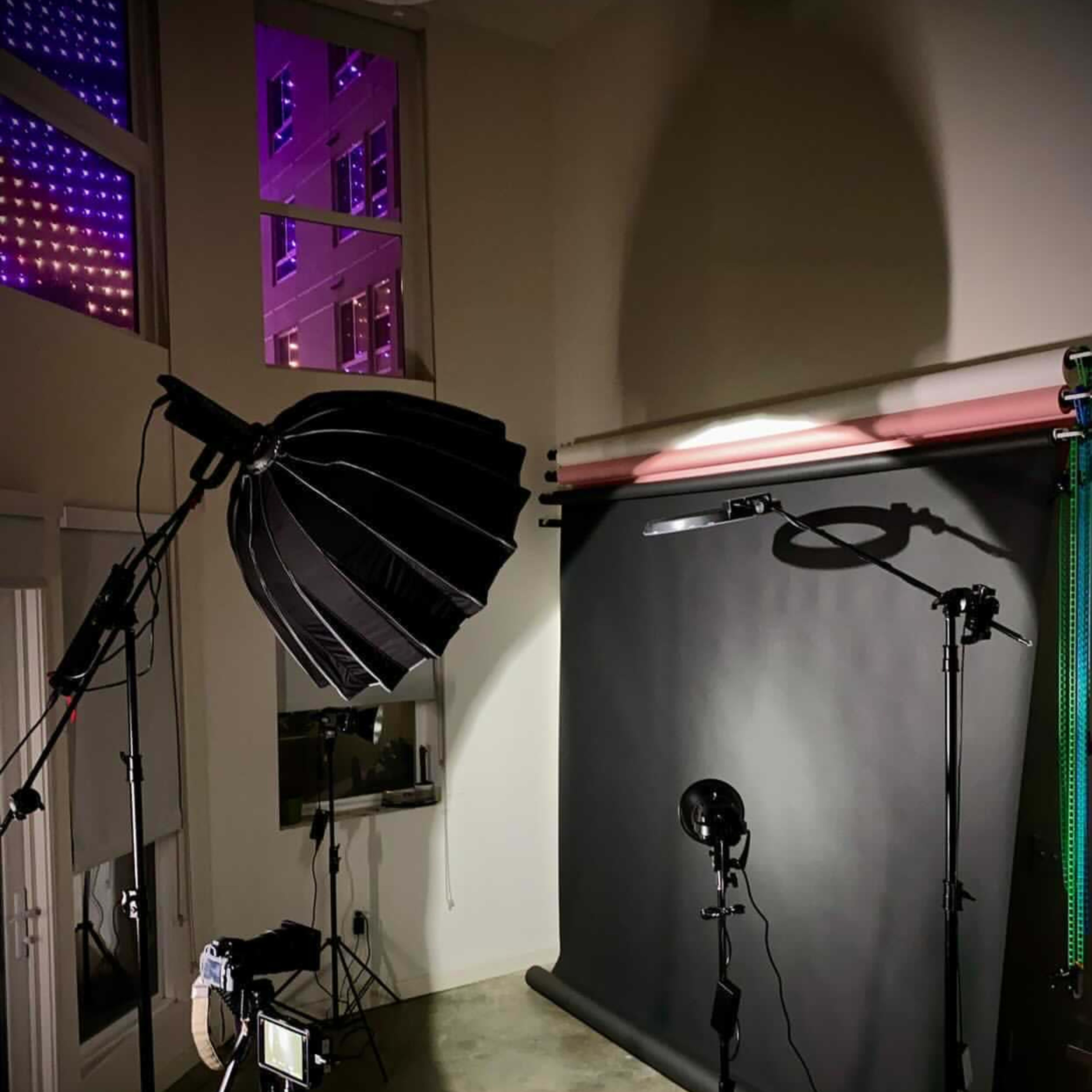 A photography studio setup featuring lighting equipment, a backdrop, and a camera.