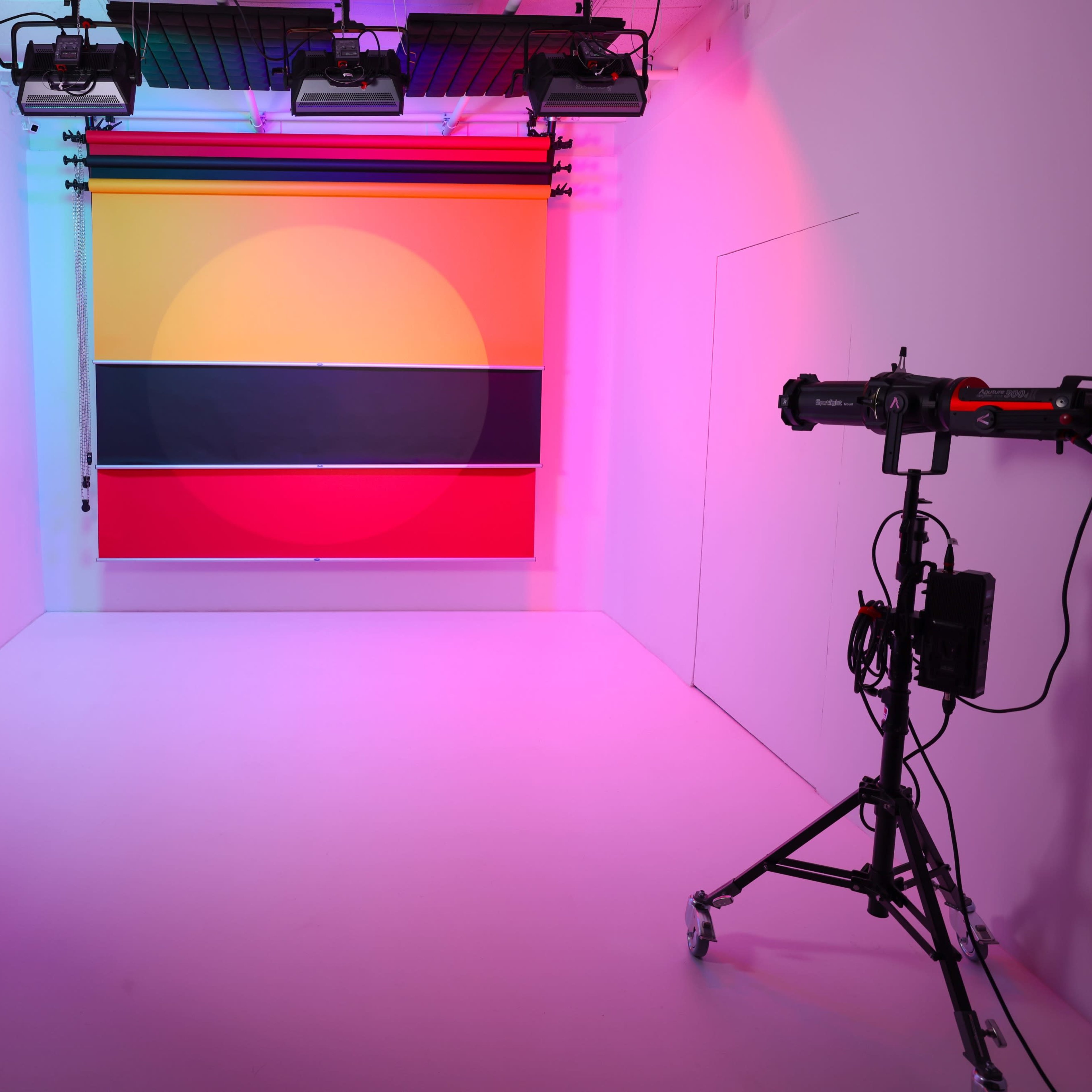 A photography studio features two lighting setups on either side of a vibrant backdrop of geometric colors.