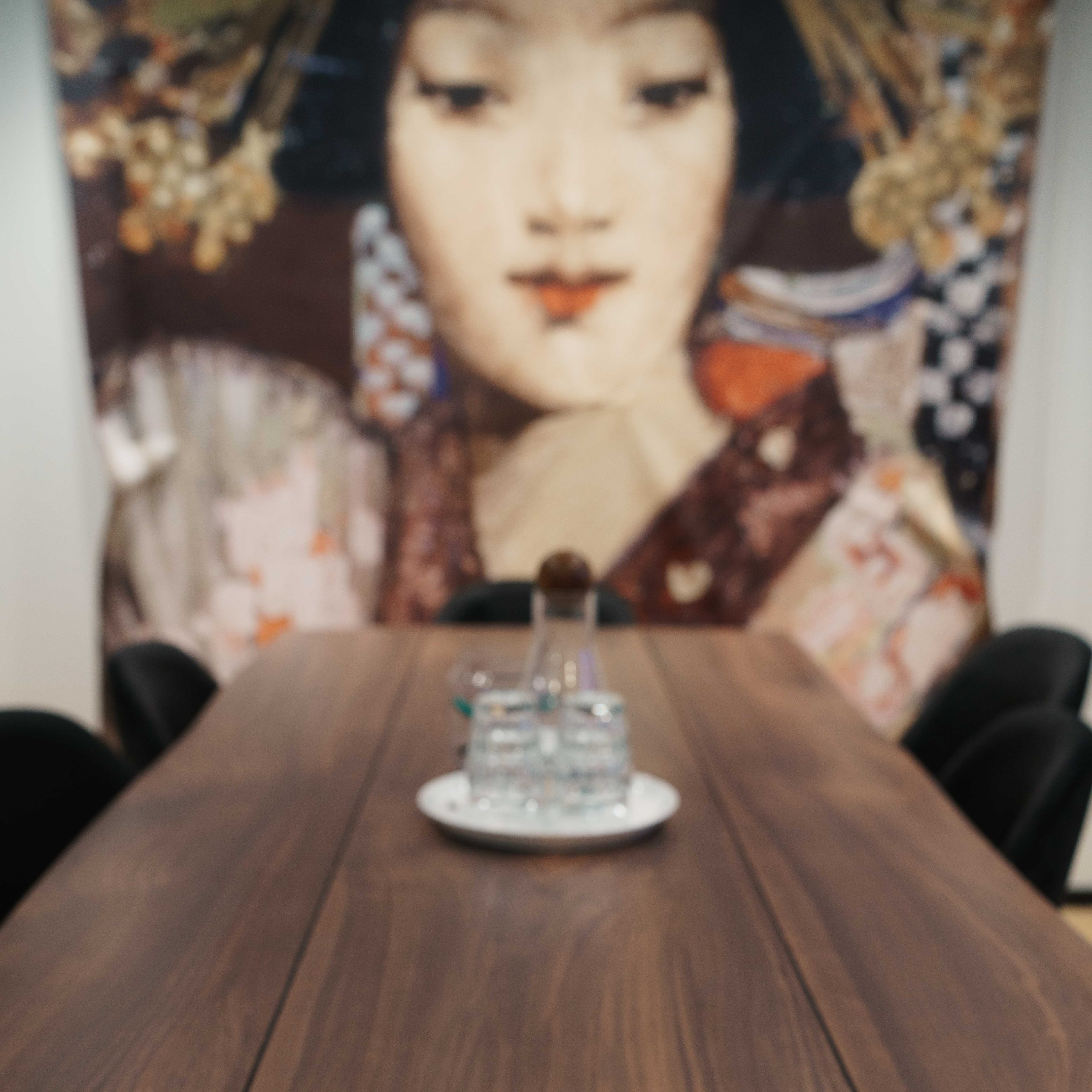 A large wooden table with a notepad and pen is positioned in front of a colorful wall art featuring a woman's face.